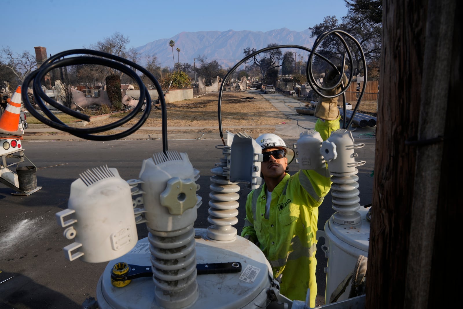 A Southern California Edison utility company worker sets up a new electric transformer to reestablish power in the area in the aftermath of the Eaton Fire, Sunday, Jan. 19, 2025, in Altadena, Calif. (AP Photo/Damian Dovarganes)