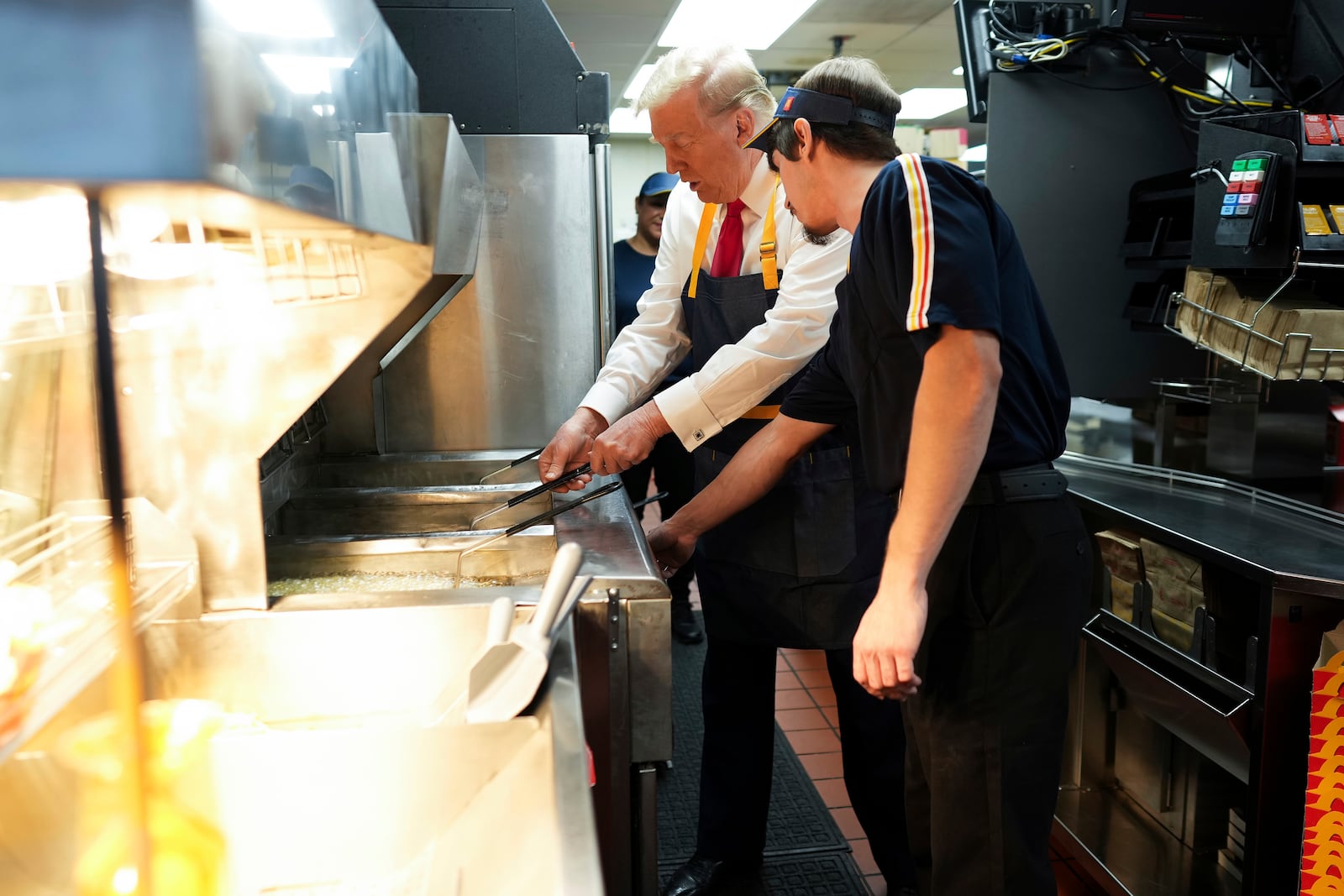 Republican presidential nominee former President Donald Trump, left, uses a frier alongside an employee during a visit to McDonald's in Feasterville-Trevose, Pa., Sunday, Oct. 20, 2024. (Doug Mills/The New York Times via AP, Pool)