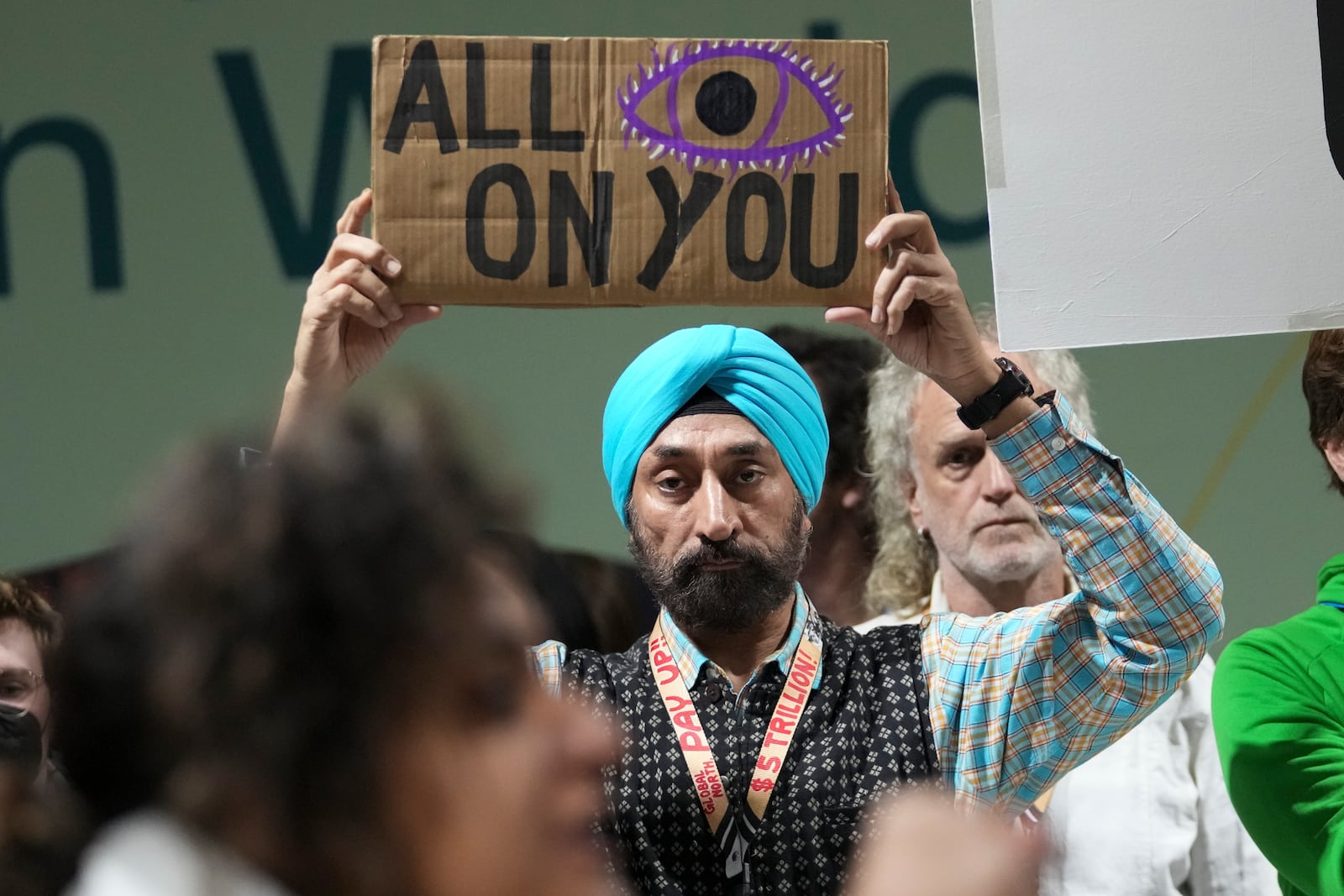 Activist Harjeet Singh holds a sign as he attends a demonstration for climate finance at the COP29 U.N. Climate Summit, Saturday, Nov. 23, 2024, in Baku, Azerbaijan. (AP Photo/Sergei Grits)