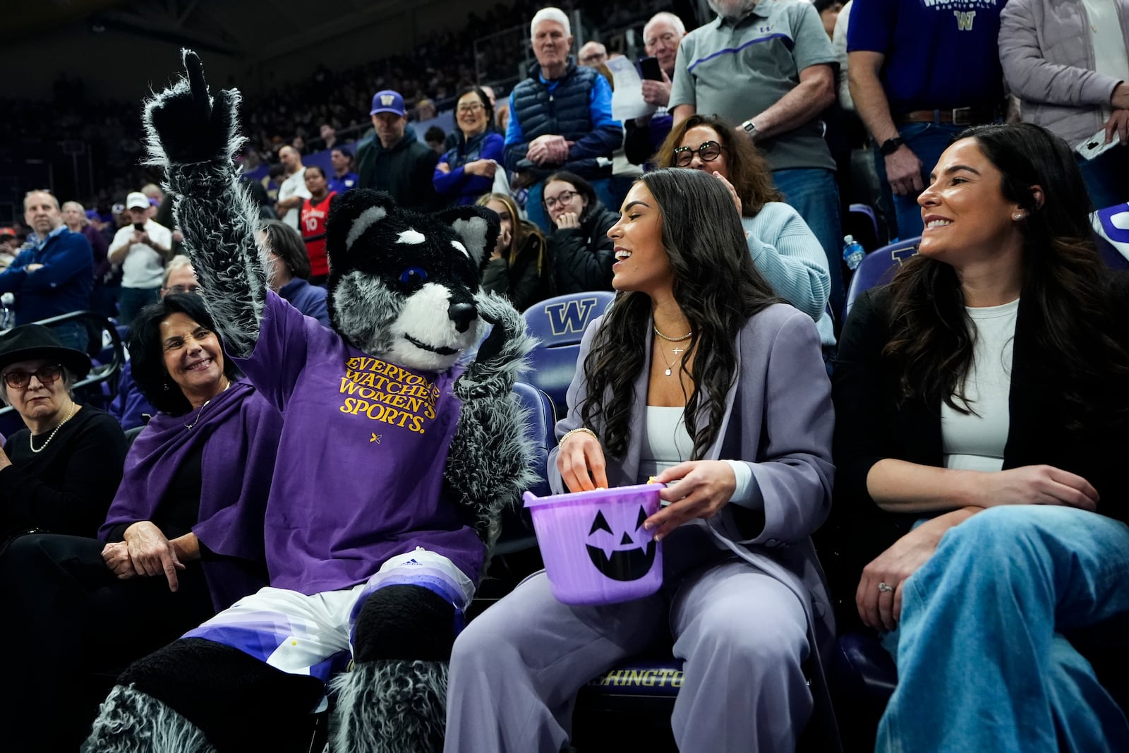 Current Las Vegas Aces player and former Washington guard Kelsey Plum, center, laughs with mascot Harry the Husky before her jersey retirement ceremony during an NCAA college basketball game between Washington and Purdue, Saturday, Jan. 18, 2025, in Seattle. (AP Photo/Lindsey Wasson)