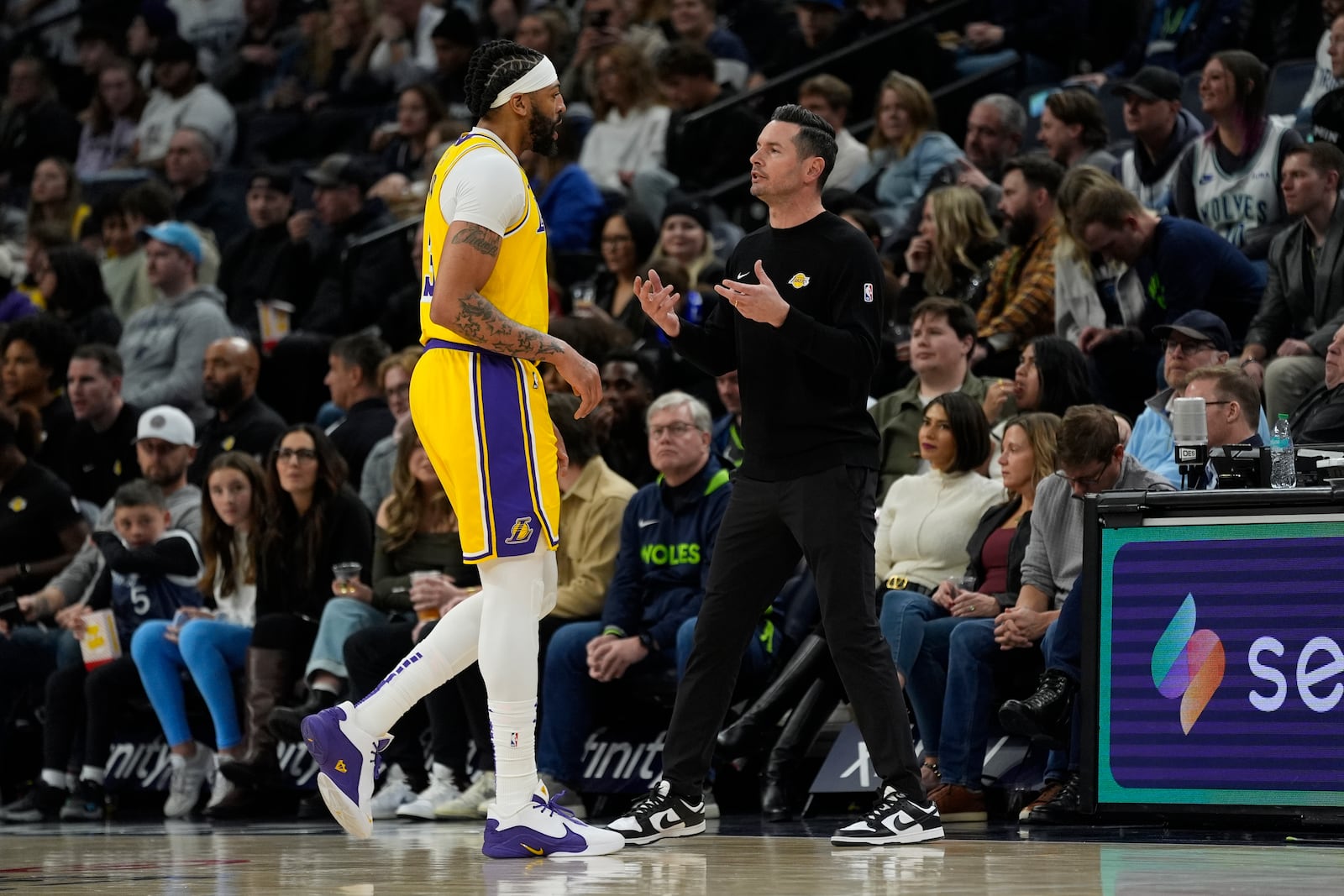 Los Angeles Lakers head coach JJ Redick, right, talks with forward Anthony Davis (3) during the first half of an NBA basketball game against the Minnesota Timberwolves, Friday, Dec. 13, 2024, in Minneapolis. (AP Photo/Abbie Parr)