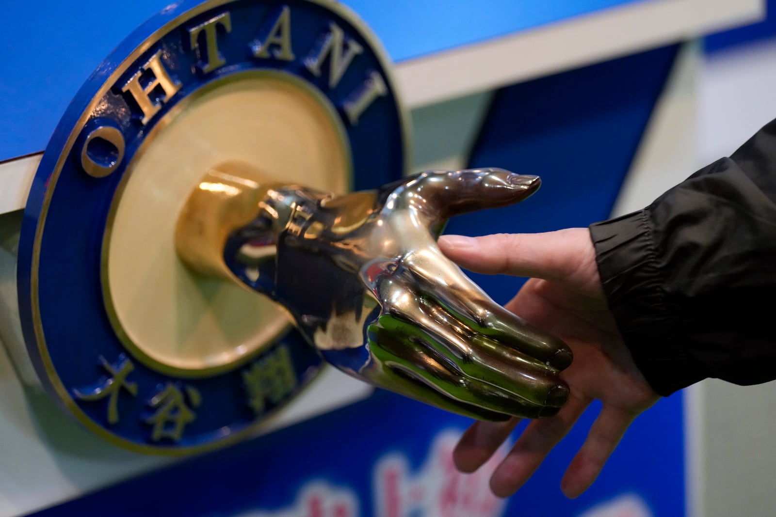 A visitor shakes hands with an iron model of Shohei Ohtani of the Los Angeles Dodgers, displayed at a local municipal government building in Oshu, northeastern Japan, the hometown of Ohtani, Tuesday, Oct. 29, 2024. (AP Photo/Eugene Hoshiko)