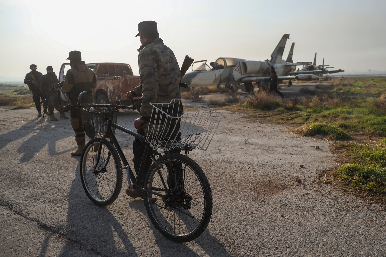 Syrian opposition fighters stand next to old military planes at the Al-Nayrab military airport after they took control of the facility in the outskirts of Aleppo, Syria, Monday, Dec. 2, 2024. .(AP Photo/Omar Albam)