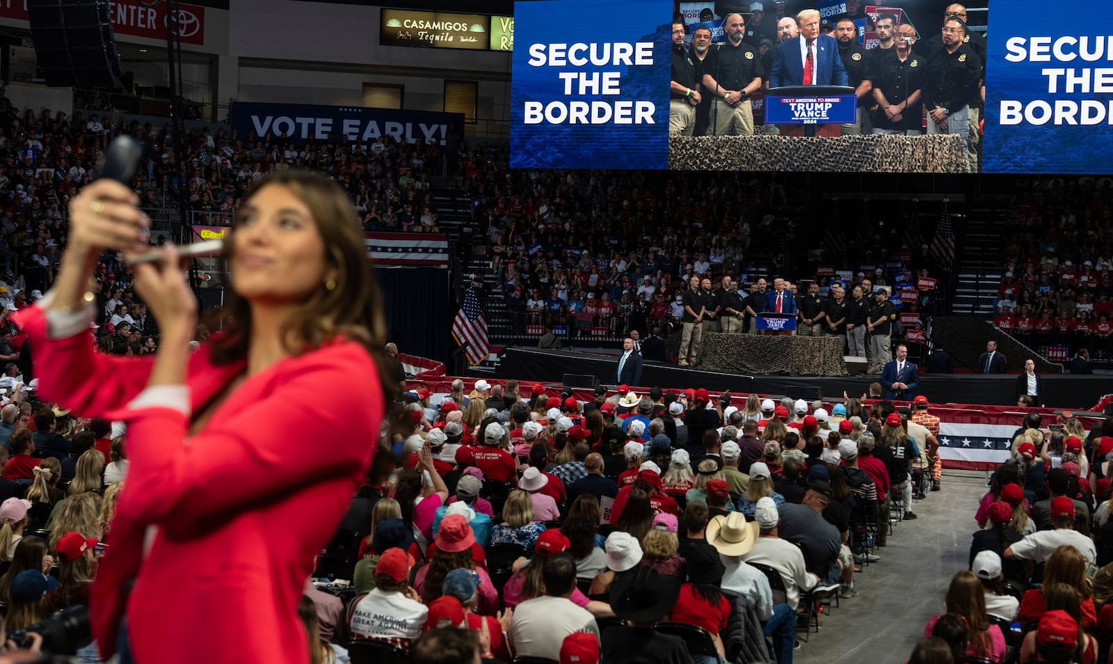 A TV reporter puts on make up while Republican presidential nominee former President Donald Trump delivers a speech during a campaign rally at the Findlay Toyota Arena, Sunday, Oct. 13, 2024, in Prescott Valley, Ariz. (AP Photo/Rodrigo Abd)