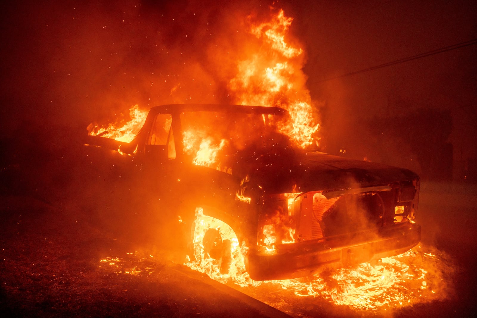 The Eaton Fire burns a vehicle Wednesday, Jan. 8, 2025 in Altadena, Calif. (AP Photo/Ethan Swope)