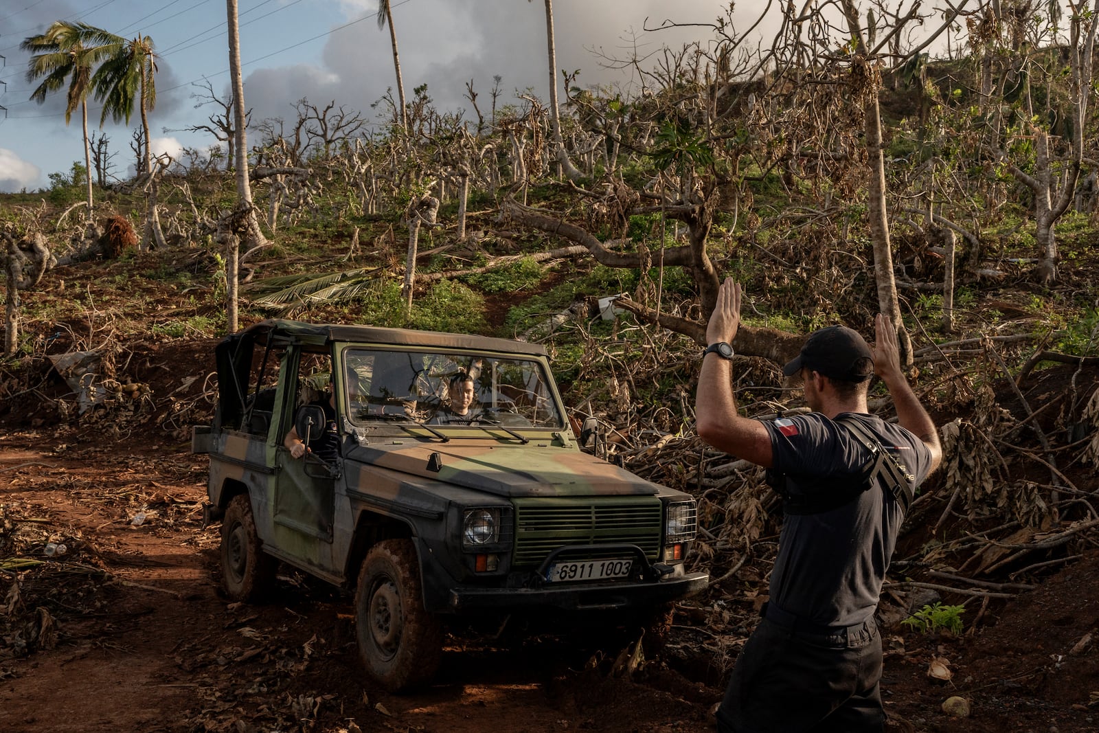 French civil security officers make their way through shredded trees heading to Mirereni, Mayotte, Friday, Dec. 20, 2024. (AP Photo/Adrienne Surprenant)