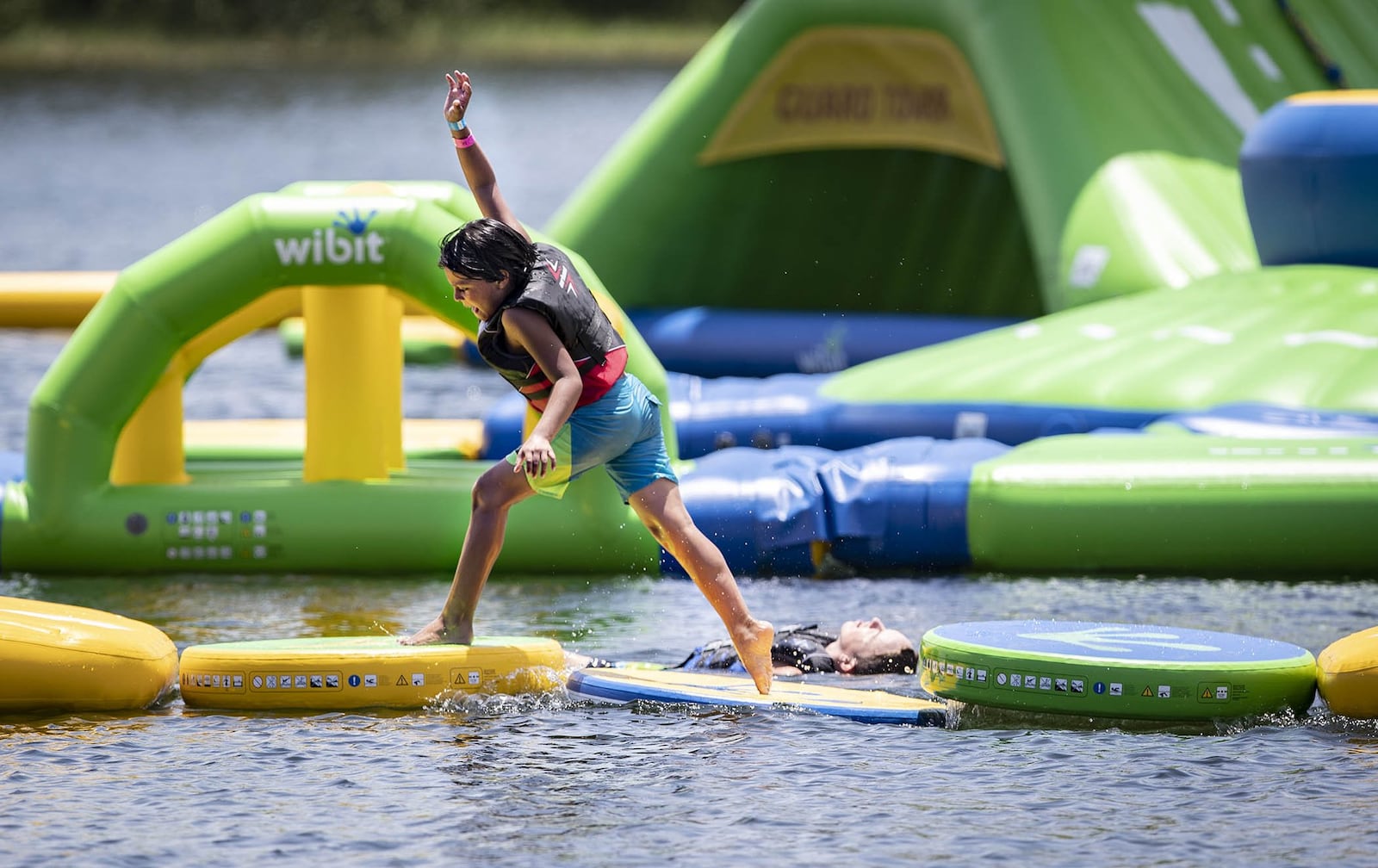 Japheth Montejo, 11, of Jupiter, runs the water obstacle course as Braxton Newman, 14, of West Palm Beach, cools off in the water at the Aqua Park at Okeeheelee Park in West Palm Beach, Florida on July 5, 2018. Shark Wake Park’s floating Aqua Park has been open for less than a week at Okeeheelee Park, but people already are expressing concerns about potential dangers there brought by alligators, snapping turtles, water moccasins and amoebas, among others. (Allen Eyestone / The Palm Beach Post)