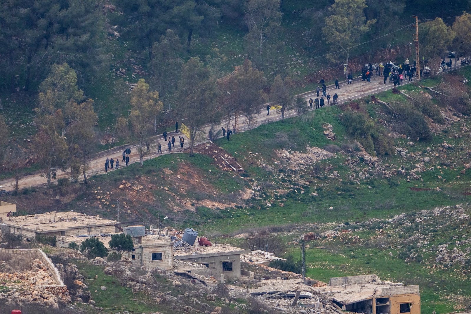 A group of people waves flags as they approach the outskirts of a southern Lebanese village, where Israeli soldiers continue to operate despite the ceasefire, as seen from northern Israel Sunday, Jan. 26, 2025. (AP Photo/Ariel Schalit)