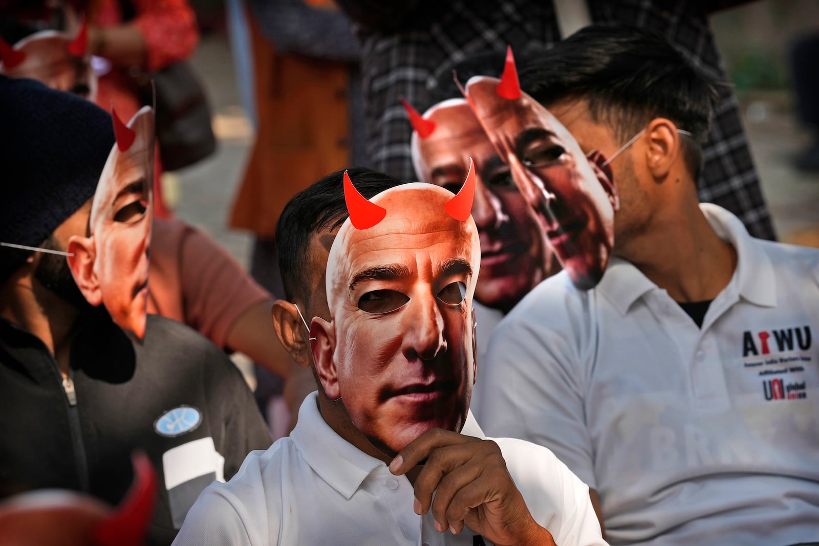 Participants wear paper masks in the likeness of Amazon's Jeff Bezos as warehouse workers and delivery drivers stage a protest against the Seattle-based company demanding higher wages and better working conditions, in New Delhi, India, Friday, Nov. 29, 2024. (AP Photo/Manish Swarup)