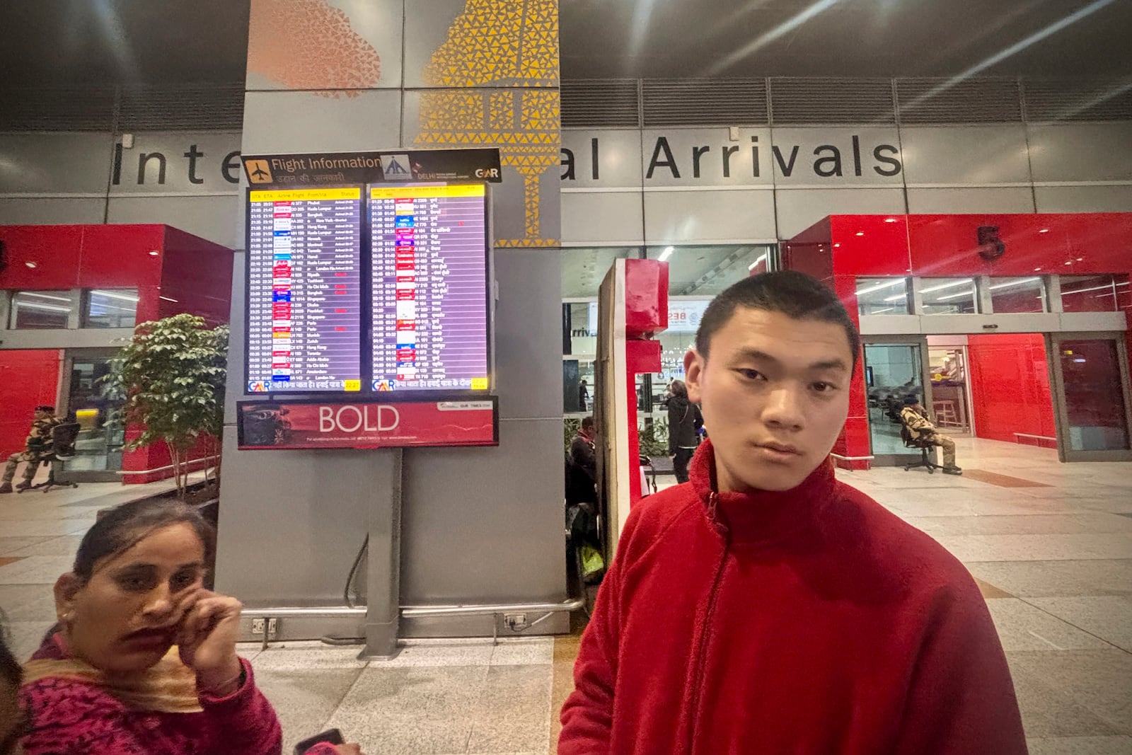 Tenzin Kunchok, right, an exiled Tibetan waiting for the arrival of a guest on the American Airlines flight AA292 from New York reacts after learning at the New Delhi international airport that the flight was diverted to Rome, instead of its scheduled arrival at New Delhi, India, Sunday, Feb. 23, 2025. (AP Photo/Manish Swarup)