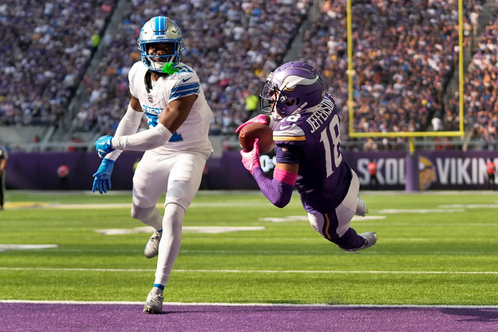 Minnesota Vikings wide receiver Justin Jefferson (18) catches 25-yard touchdown pass as Detroit Lions cornerback Amik Robertson (21) defends during the second half of an NFL football game Sunday, Oct. 20, 2024, in Minneapolis. (AP Photo/Abbie Parr)