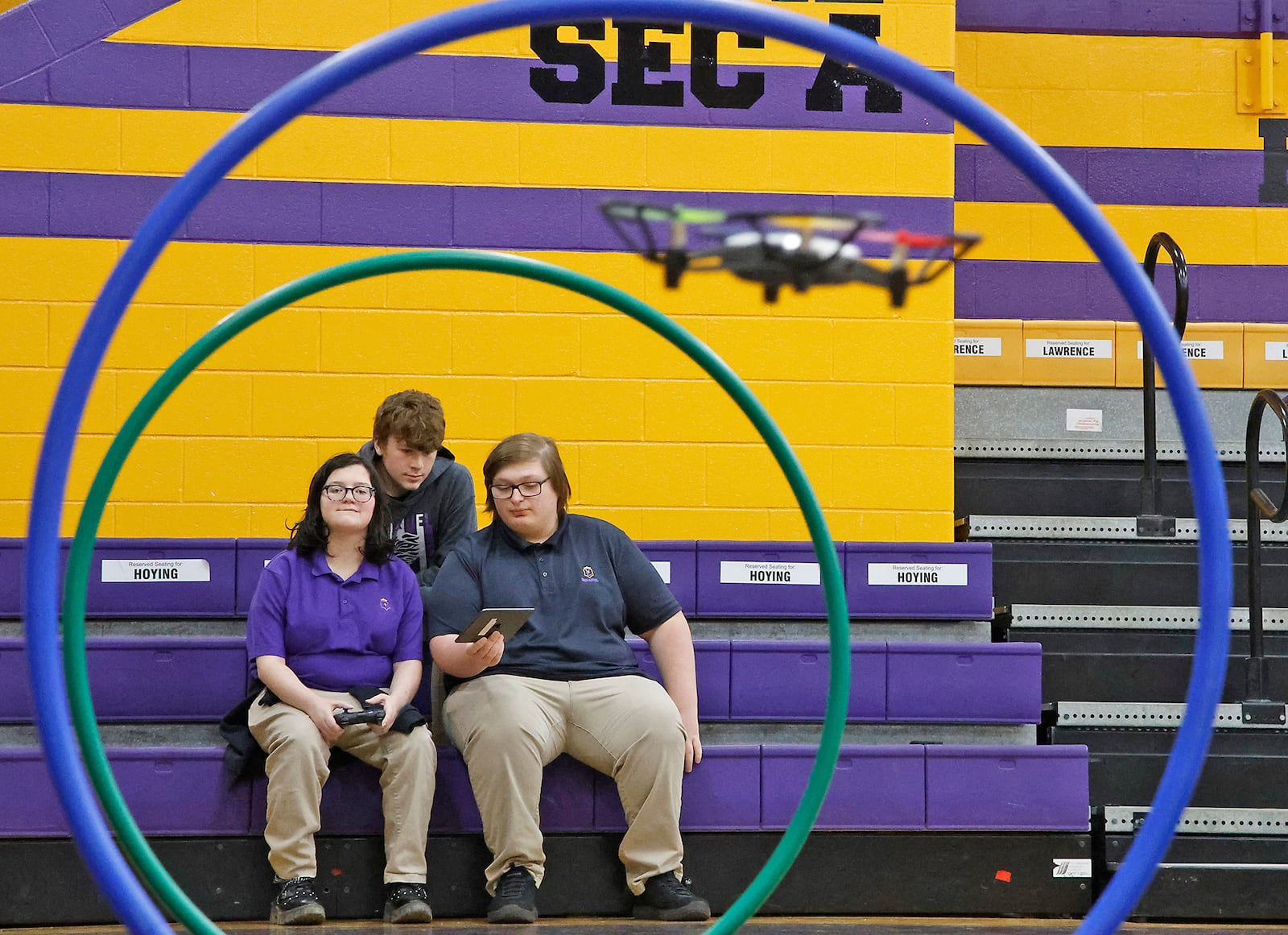 Emmanuel Christian Academy freshmen, from left, Hannah Barnard, Jacob Bailes and Braden Robbins guide a drone through an obstacle course in the school's gym Tuesday, April 23, 2024. The students were participating in the school's Aerospace Institute. BILL LACKEY/STAFF