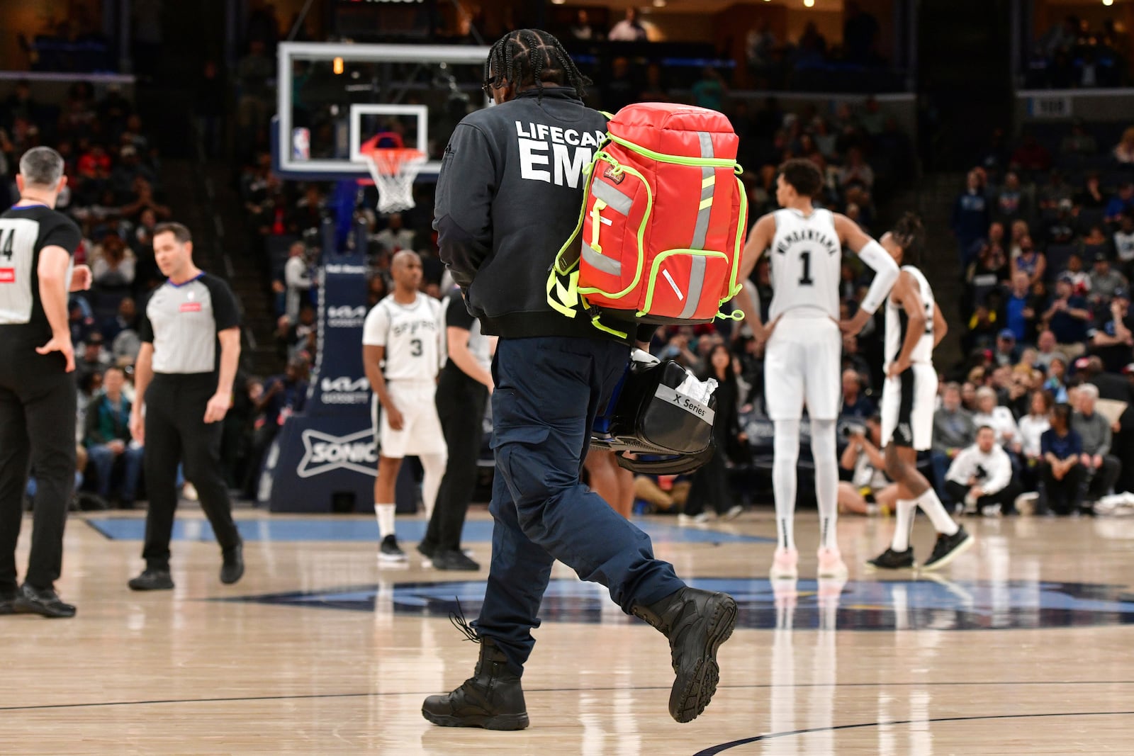 An EMT runs across the court to help assist a man experiencing a medical emergency just before tipoff of an NBA basketball game between the San Antonio Spurs and the Memphis Grizzlies, Monday, Feb. 3, 2025, in Memphis, Tenn. (AP Photo/Brandon Dill)