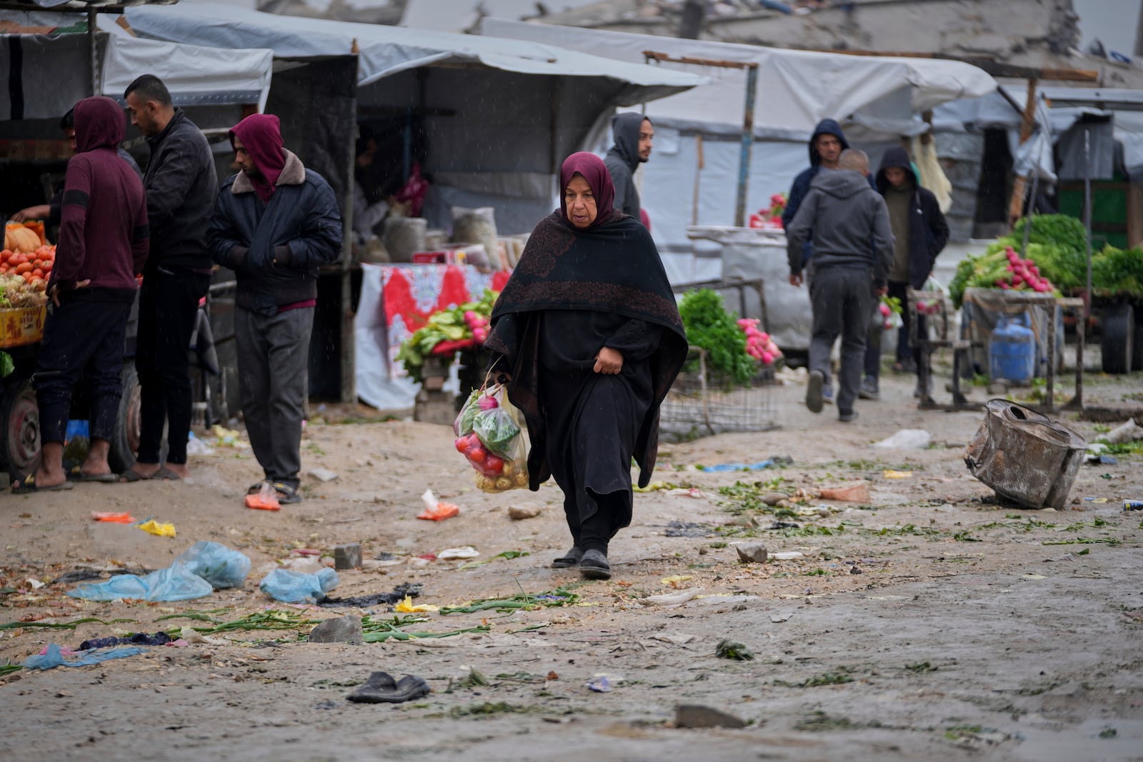 A woman carries groceries after shopping at a street market in Beit Lahiya, northern Gaza Strip, Thursday March 6, 2025.(AP Photo/Abdel Kareem Hana)