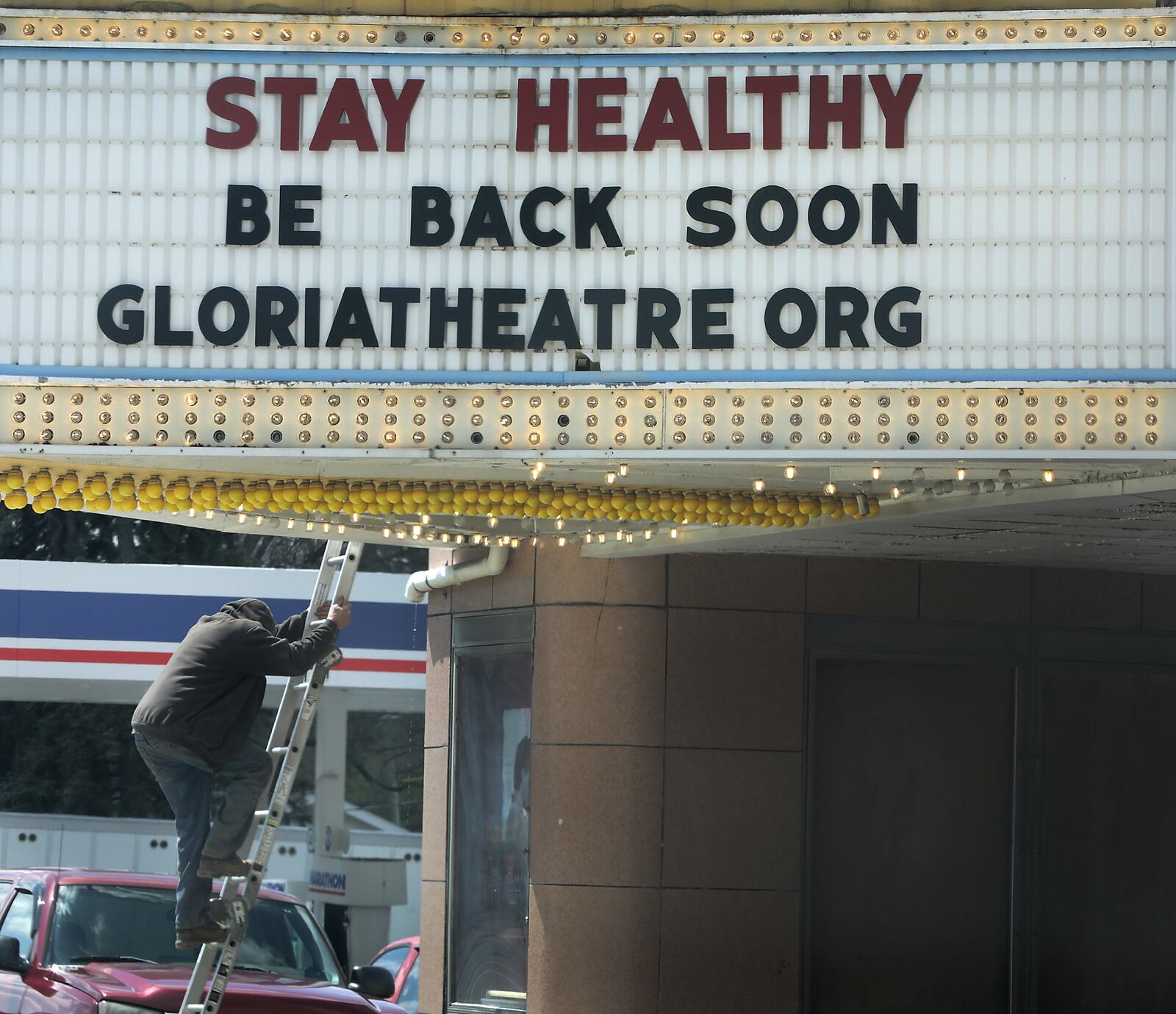 A worker climbs down a ladder from the roof of the Gloria Theatre in Urbana on April 16. BILL LACKEY/STAFF