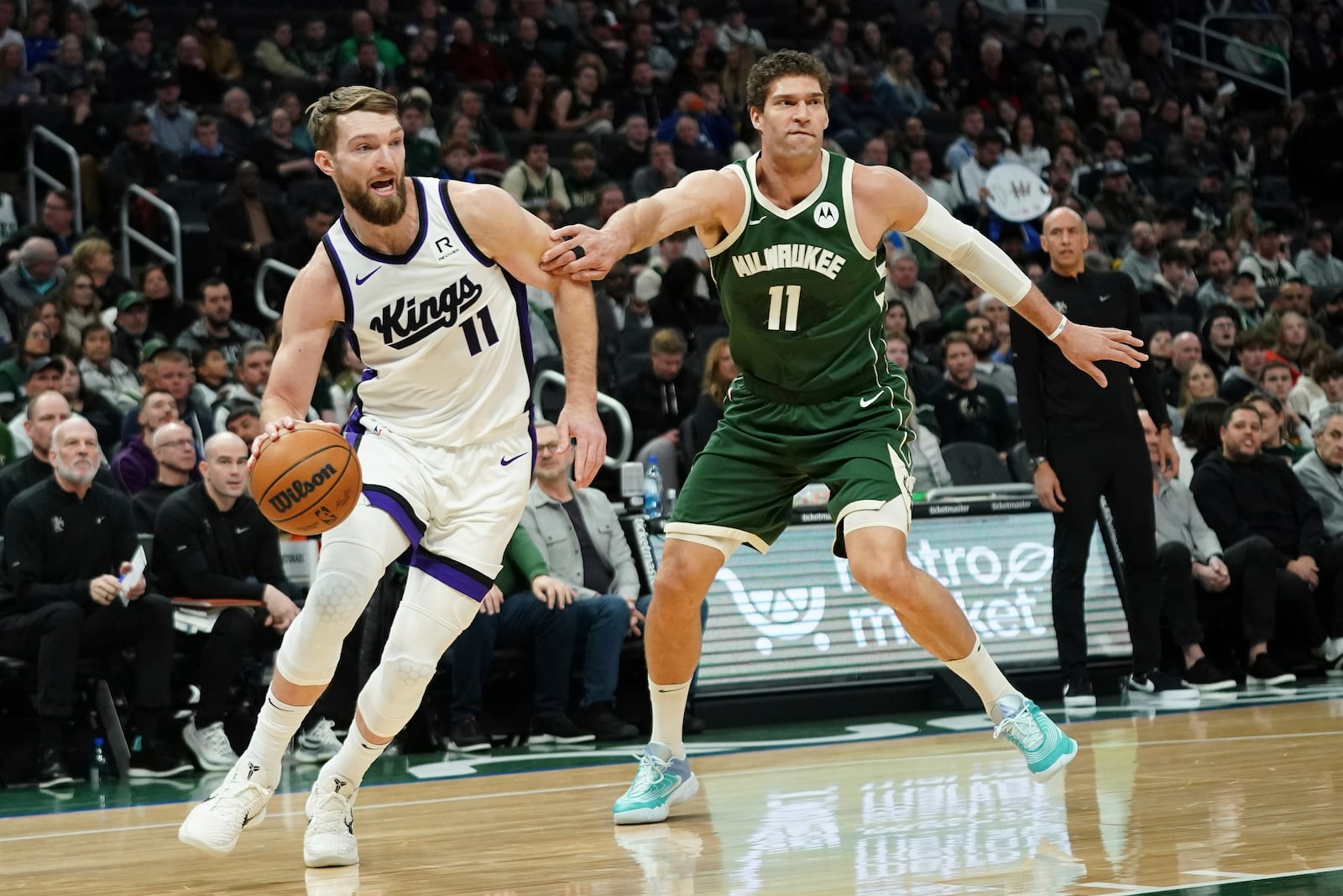 Sacramento Kings' Domantas Sabonis, left, drives to the basket against Milwaukee Bucks' Brook Lopez during the first half of an NBA basketball game, Tuesday, Jan. 14, 2025, in Milwaukee. (AP Photo/Aaron Gash)