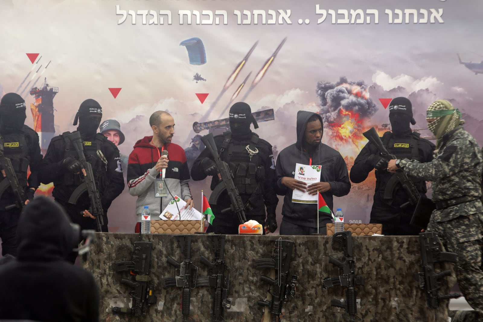 Israeli hostages Tal Shoham left, and Avera Mengisto are escorted by Hamas fighters before being handed over to the Red Cross in Rafa, southern Gaza Strip, on Saturday, Feb. 22, 2025. (AP Photo/Jehad Alshrafi)