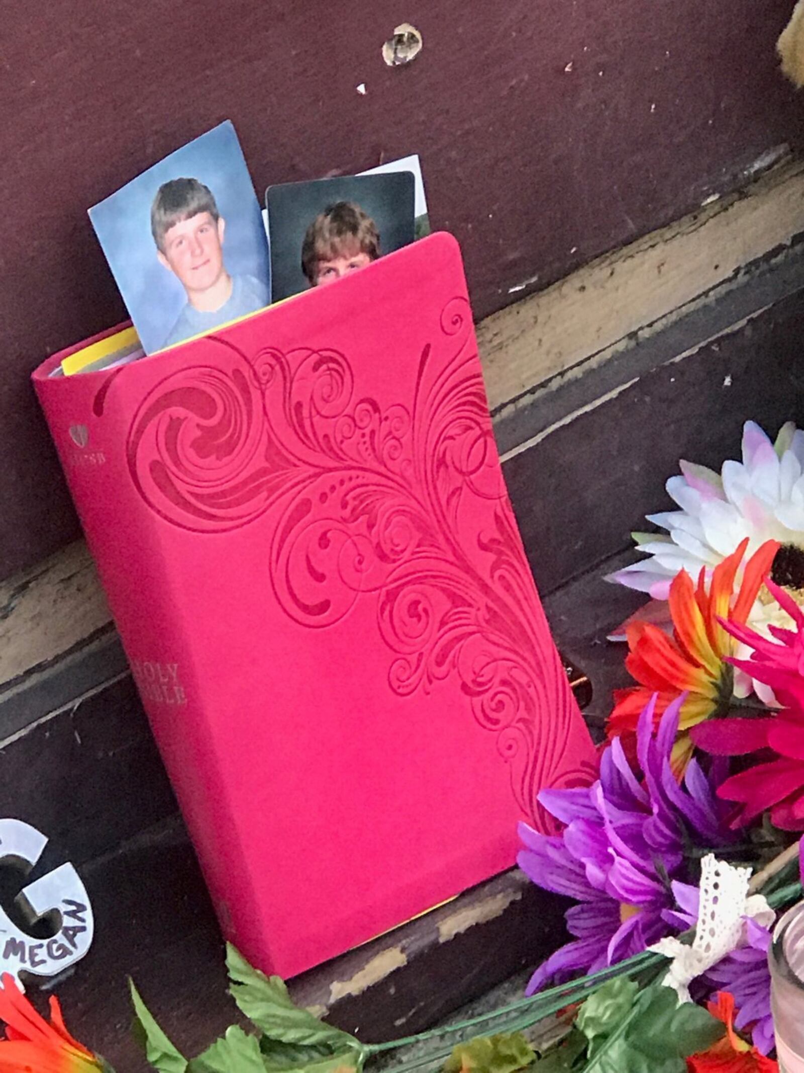 Two photos of a young a young Logan Turner peek from a pink-covered bible that was initially propped up against the door of Ned Peppers and now remains part of the memorial outside the Oregon District bar. Tom Archdeacon/STAFF