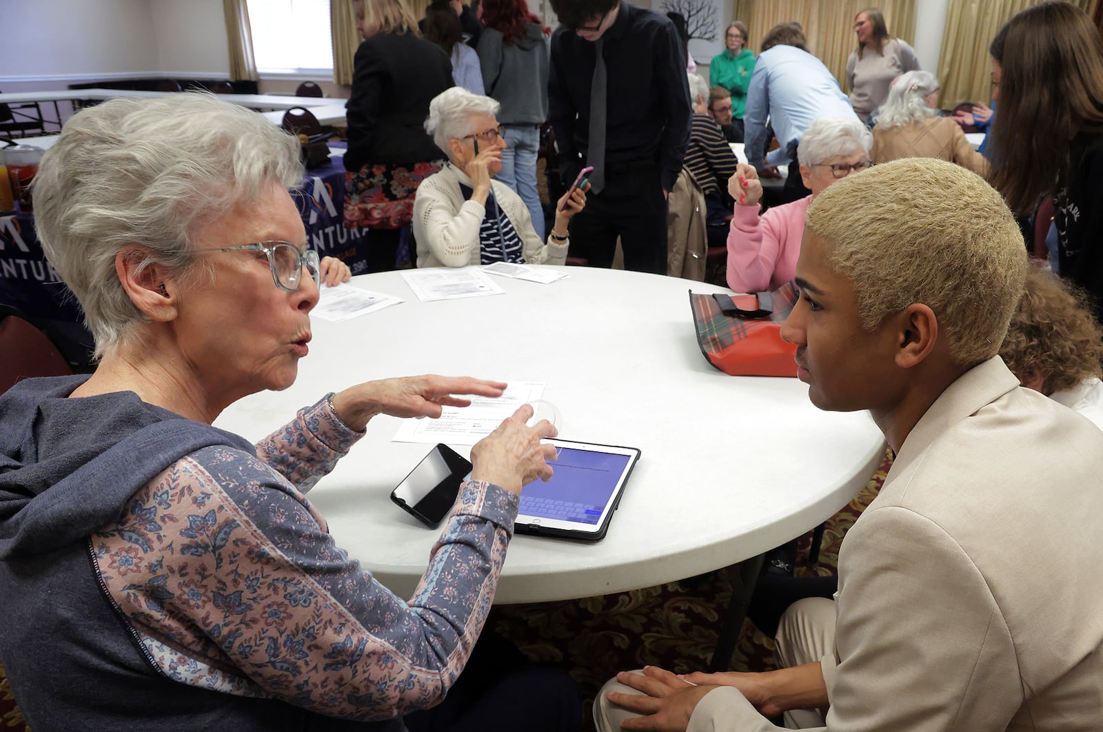 Joyce Neese, a resident at Oakwood Village retirement community, asks Alex Grubb, a CTC Cybersecurity student, a question about her laptop computer Monday, Feb. 24, 2024. Clayton and several other cybersecurity students visited Oakwood Village to talk about how to avoid scams on the internet and answer any questions the residents had about their portable devices. BILL LACKEY/STAFF