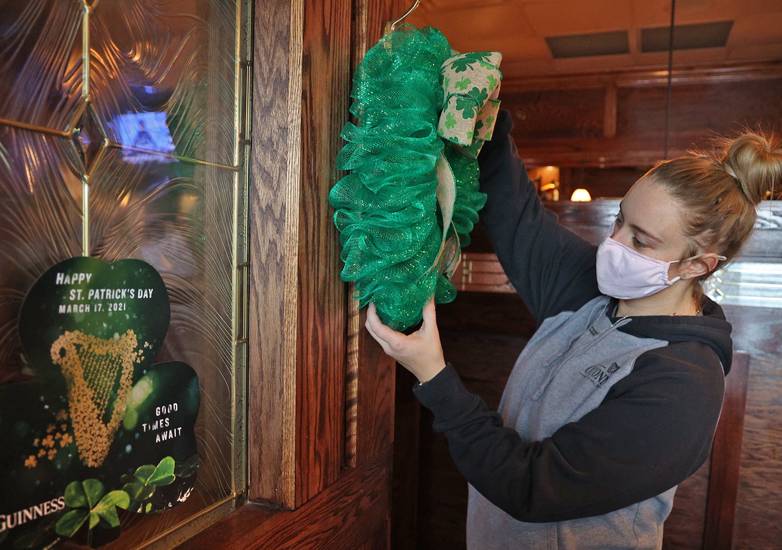 Kadie Cordle, an employee at O'Conner's Irish Pub, decorates for the holiday Monday. BILL LACKEY/STAFF