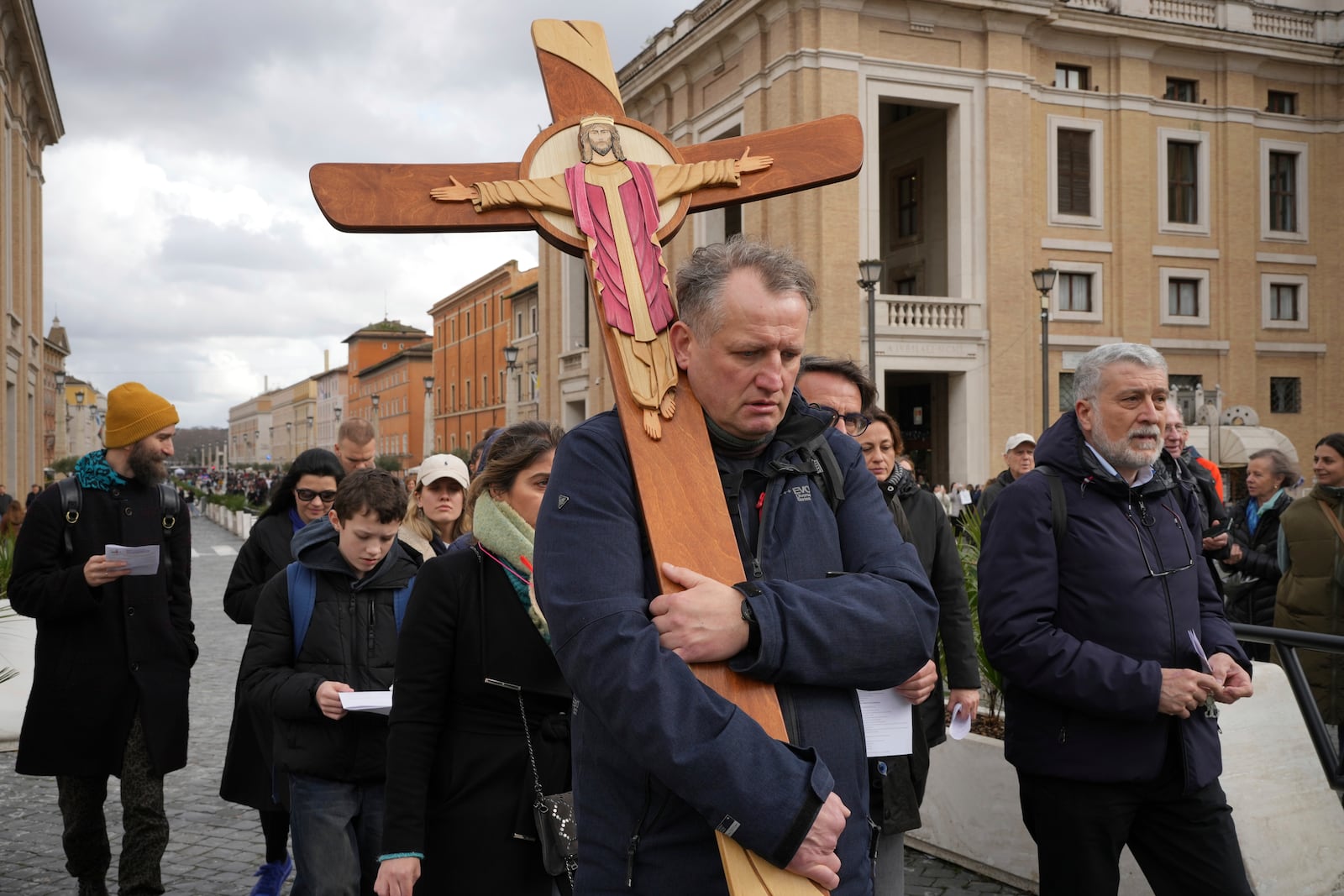 Pilgrims for the jubiliar year 2025 carrying a wooden cricifix arrive in St. Peter's Square at The Vatican, Friday, Feb. 14, 2025, hours after Pope Francis was hospitalized to undergo some necessary diagnostic tests and to continue his ongoing treatment for bronchitis. (AP Photo/Alessandra Tarantino)