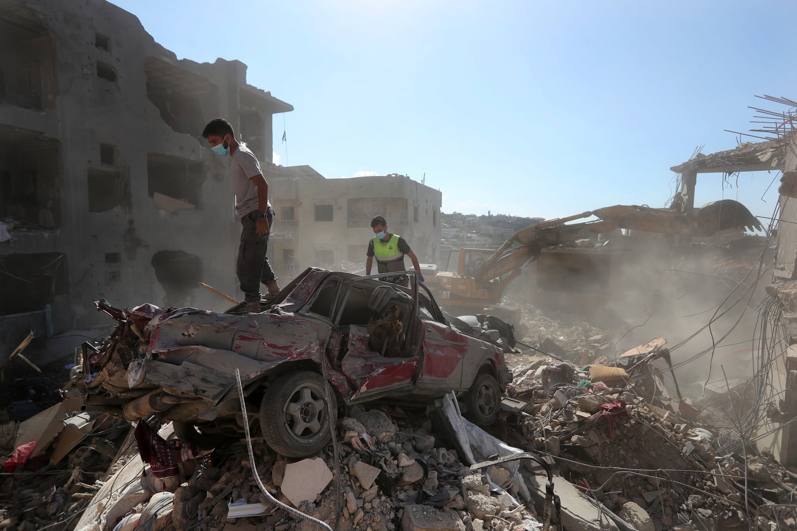 Rescue worker stand on a destroyed car over the rubble of a destroyed building hit by an Israeli airstrike in Saksakiyeh village, south Lebanon, Tuesday, Nov. 12, 2024. (AP Photo/Mohammed Zaatari)