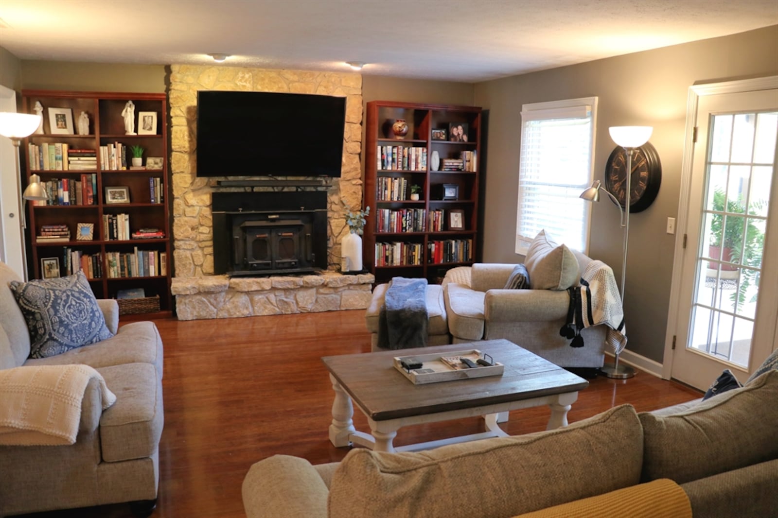 In the family room, a stone fireplace has a raised hearth and wood-burning insert. 