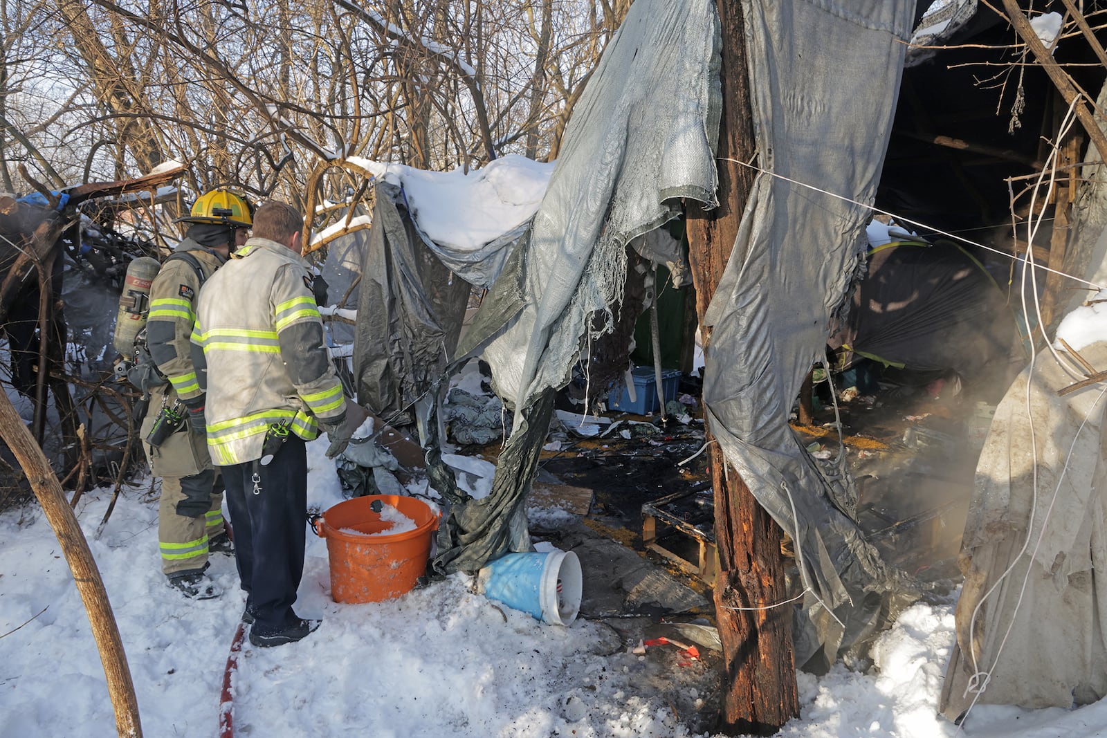 Members of the Springfield Fire & Rescue Division investigate a fire at a homeless encampment along East High Street Thursday, Jan. 9, 2025. The residents of the encampment were not present when the fire department arrived. BILL LACKEY/STAFF