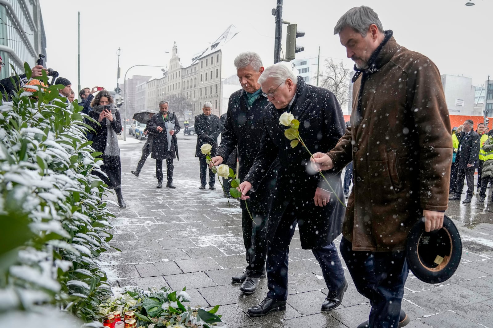 Markus Soeder, Prime Minister of Bavaria, German President Frank-Walter Steinmeier and Dieter Reiter (SPD),Mayor of Munich, from right, bring flowers to the site where a car crashed into a Ver.di demonstration the day before, Munich, Germany, Friday, Feb. 14, 2025. (AP Photo/Ebrahim Noroozi)