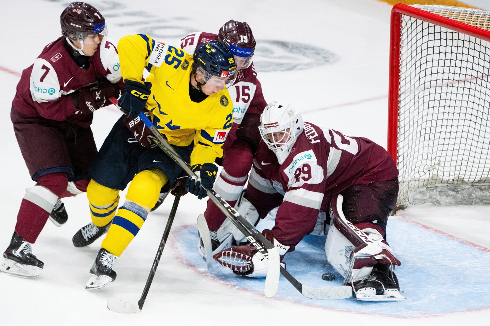 Team Sweden forward Otto Stenberg (25) tries to score on Team Latvia goaltender Linards Feldbergs (29) as Latvia forward Davis Livsics (7) and defenseman Darels Uljanskis (15) defend during the third period of an IIHF World Junior Hockey Championship quarterfinal match in Ottawa, Ontario Thursday, Jan. 2, 2025. (Spencer Colby/The Canadian Press via AP)