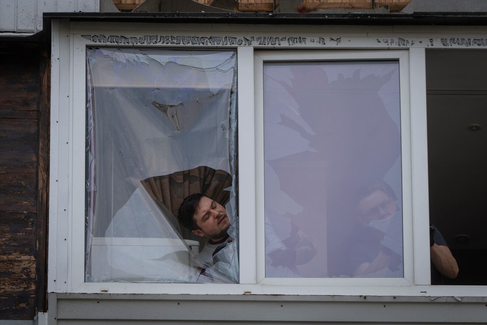 Residents clean up the damaged apartment in a multi-storey house after Russia's night drone attack, in Kyiv, Ukraine, Sunday, March 23, 2025. (AP Photo/Efrem Lukatsky)