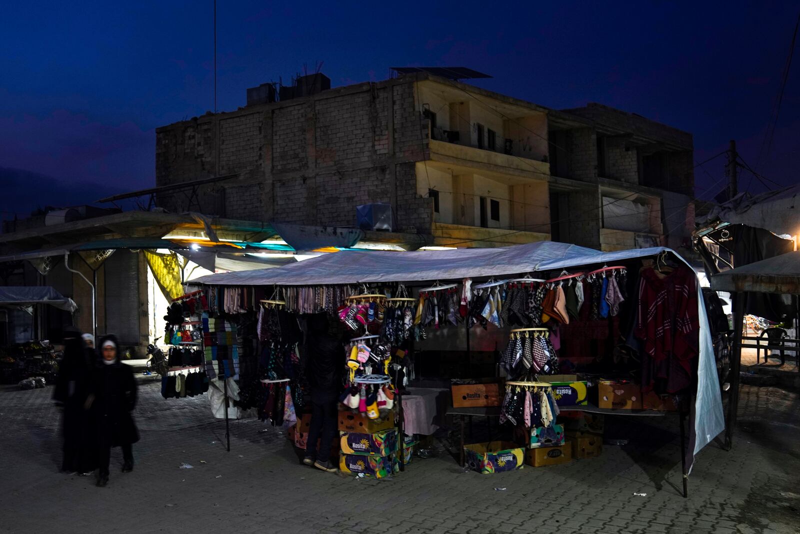 A street vendor displays clothing for sale in an open market in Atareb, northern the city of Aleppo, Syria, Sunday, Dec. 15, 2024. (AP Photo/Khalil Hamra)