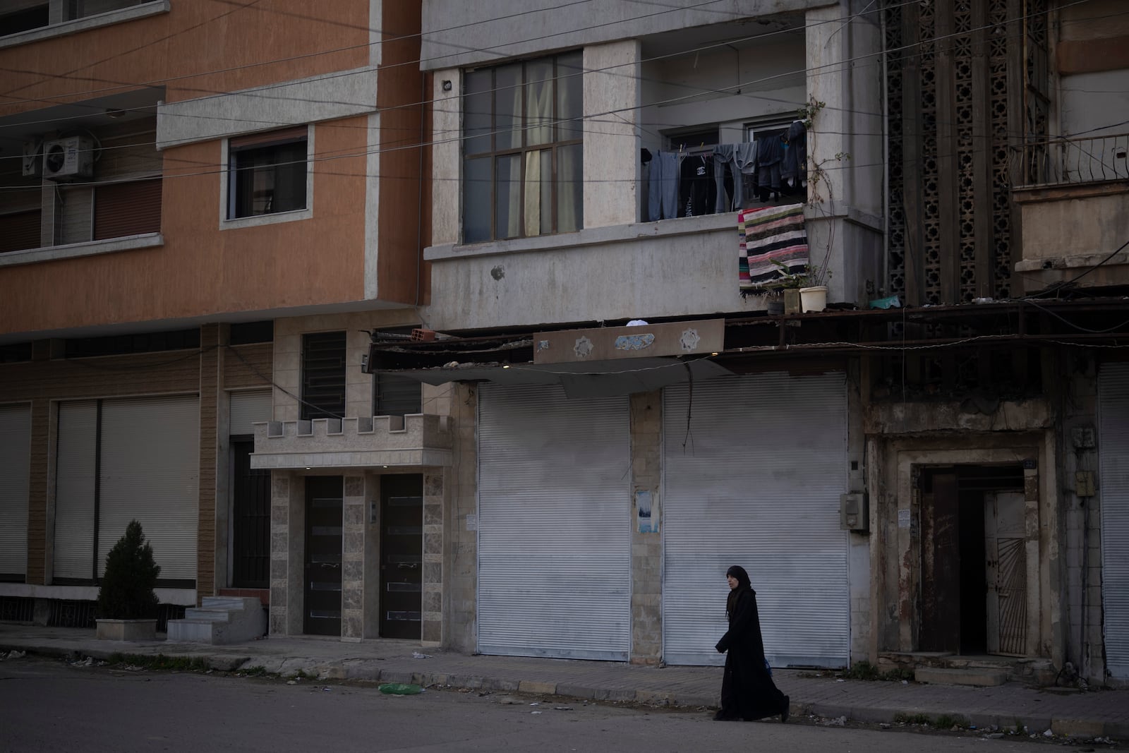 A woman walks on a street in an Alawite neighbourhood, in Homs, Syria, Thursday, Dec. 26, 2024. (AP Photo/Leo Correa)