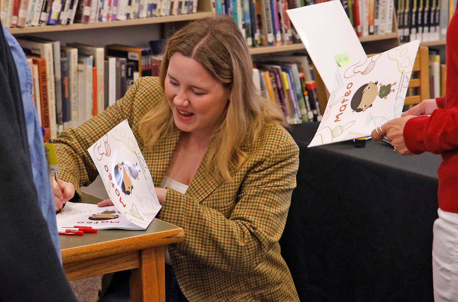 Hannah Spitzer, a former Shawnee High School student, autographs coppies of the children's book she wrote and illustrated Friday, April 19, 2024 at her alma mater. BILL LACKEY/STAFF