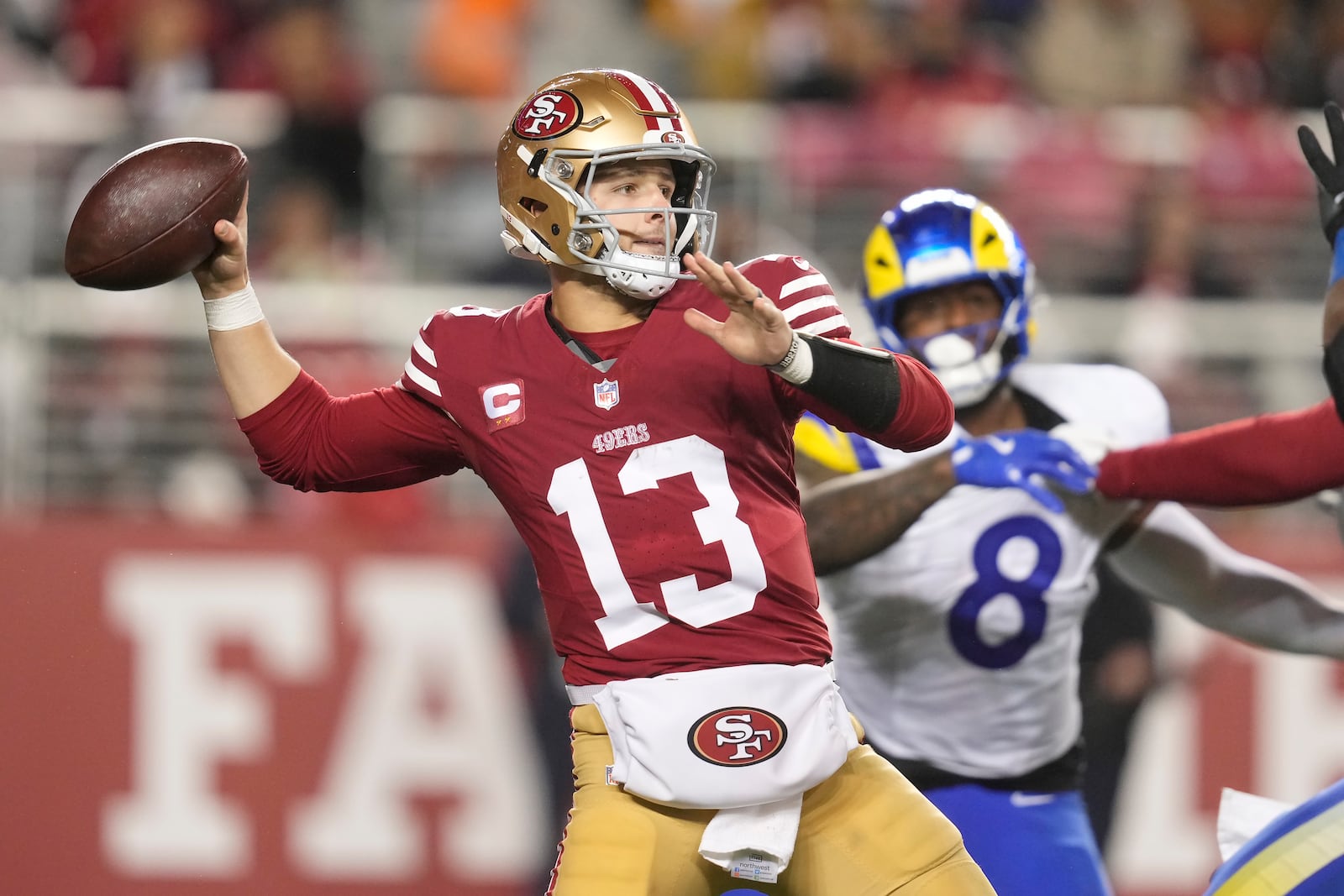 San Francisco 49ers quarterback Brock Purdy (13) passes as Los Angeles Rams linebacker Jared Verse (8) applies pressure during the second half of an NFL football game in Santa Clara, Calif., Thursday, Dec. 12, 2024. (AP Photo/Godofredo A. Vásquez)