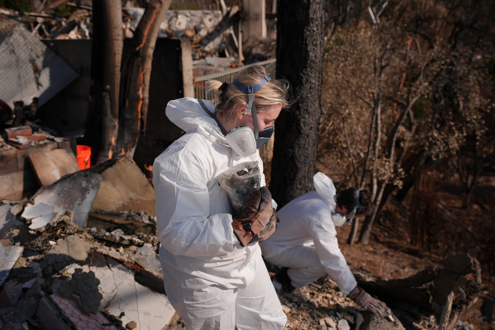 Katelyn White, left, and her husband John Borbone search through their fire-ravaged property after the Palisades Fire in the Pacific Palisades neighborhood of Los Angeles, Tuesday, Jan. 28, 2025. (AP Photo/Jae C. Hong)