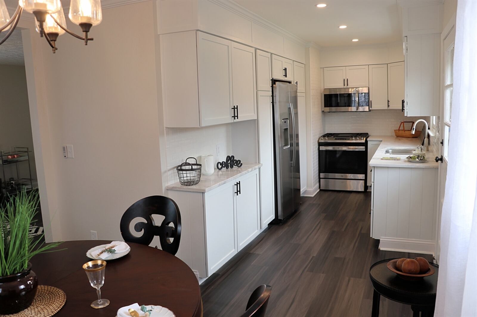 White cabinetry fills every wall space in the kitchen. Two pantry cabinets flank the refrigerator. At the end of the kitchen is the range with microwave above. CONTRIBUTED BY KATHY TYLER