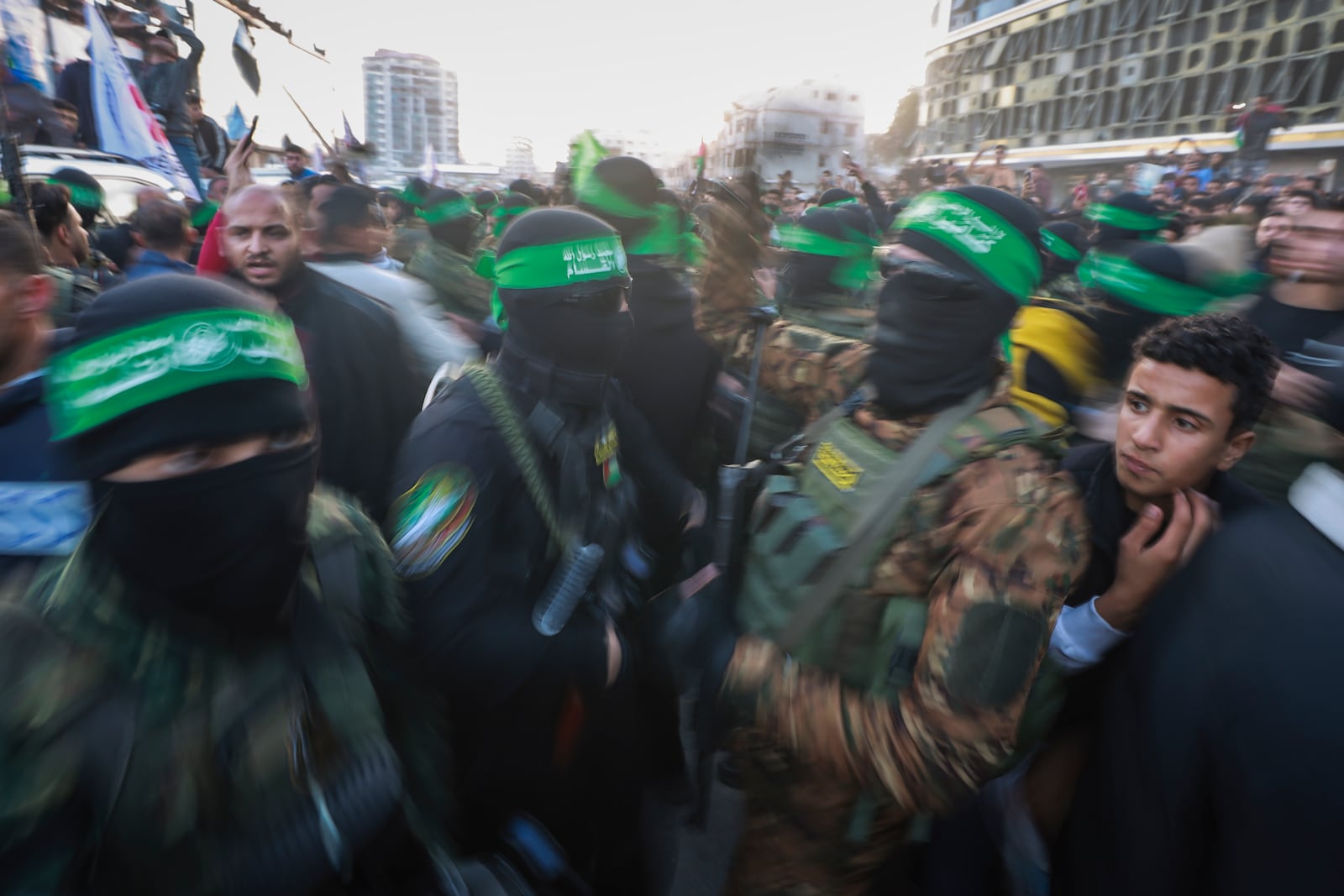 Hamas fighters attempt to control the crowd as Red Cross vehicles maneuver to collect Israeli hostages released under a ceasefire agreement between Israel and Hamas, in Gaza City, Sunday, Jan. 19, 2025. (AP Photo/Abed Hajjar)