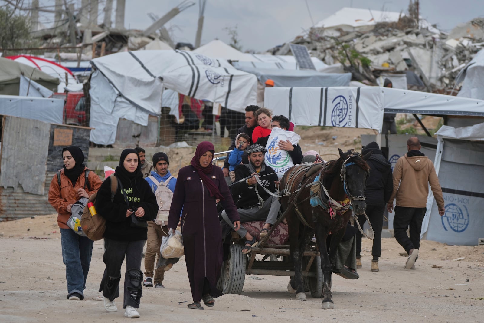 Displaced Palestinians, carrying their belongings, move away from the areas where the Israeli army is operating after Israel's renewed offensive in the Gaza Strip, on the outskirts of Beit Lahia, Thursday, March 20, 2025. (AP Photo/Jehad Alshrafi)