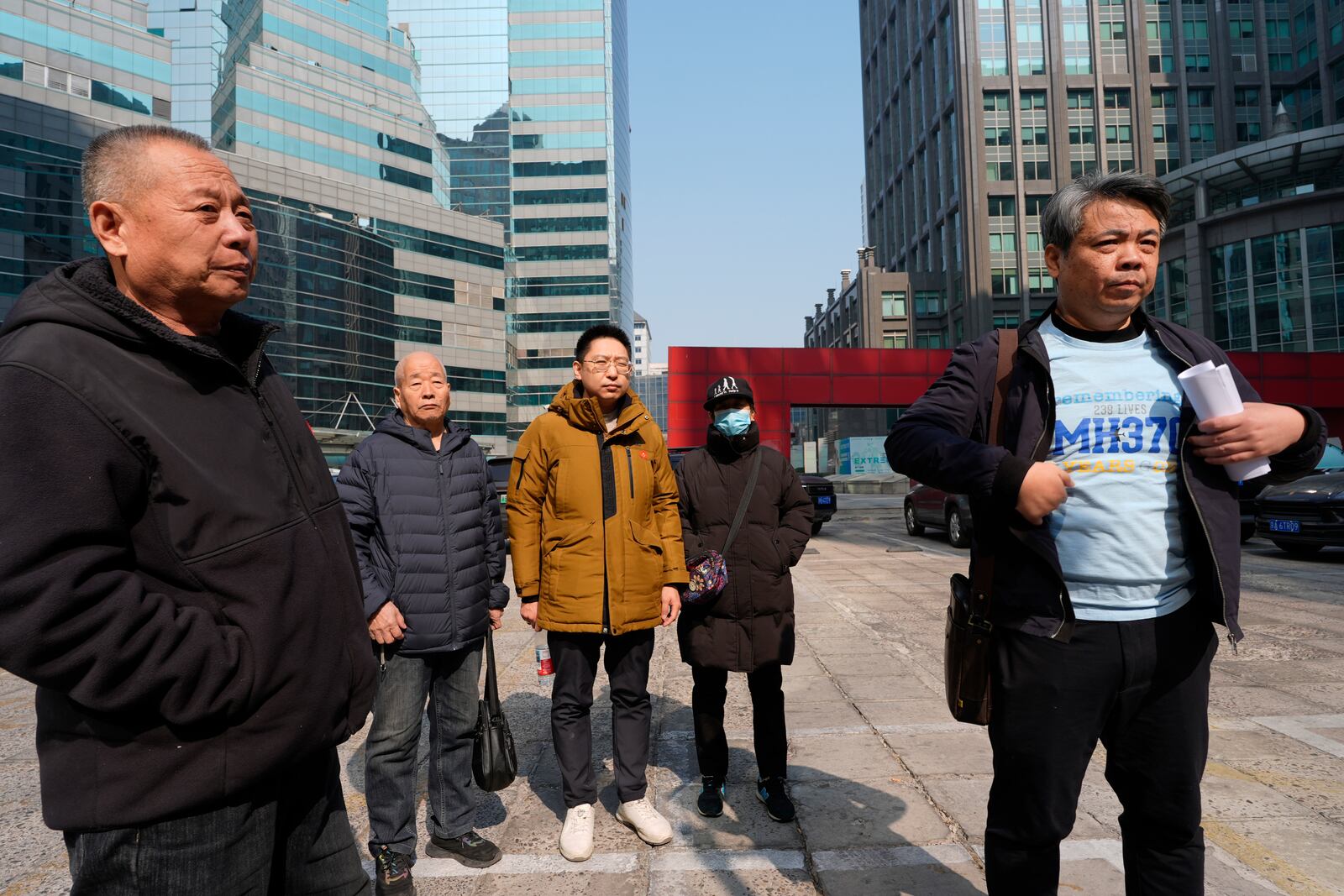 Jiang Hui, right, whose mother was on the missing MH370 Malaysia Airlines passenger jet, wears a shirt "Remembering 239 Lives, MH370" as he talks to media near other family members of victims Saturday, March 8, 2025, in Beijing, China. (AP Photo/Ng Han Guan)