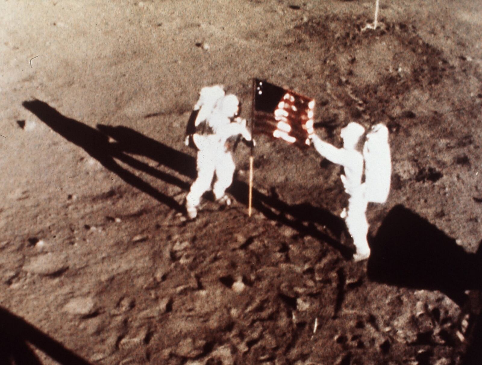 FILE - In this July 20, 1969 file photo, Apollo 11 astronauts Neil Armstrong and Edwin E. “Buzz” Aldrin, the first men to land on the moon, plant the U.S. flag on the lunar surface. Photo was made by a 16mm movie camera inside the lunar module, shooting at one frame per second. (AP Photo/NASA, file)