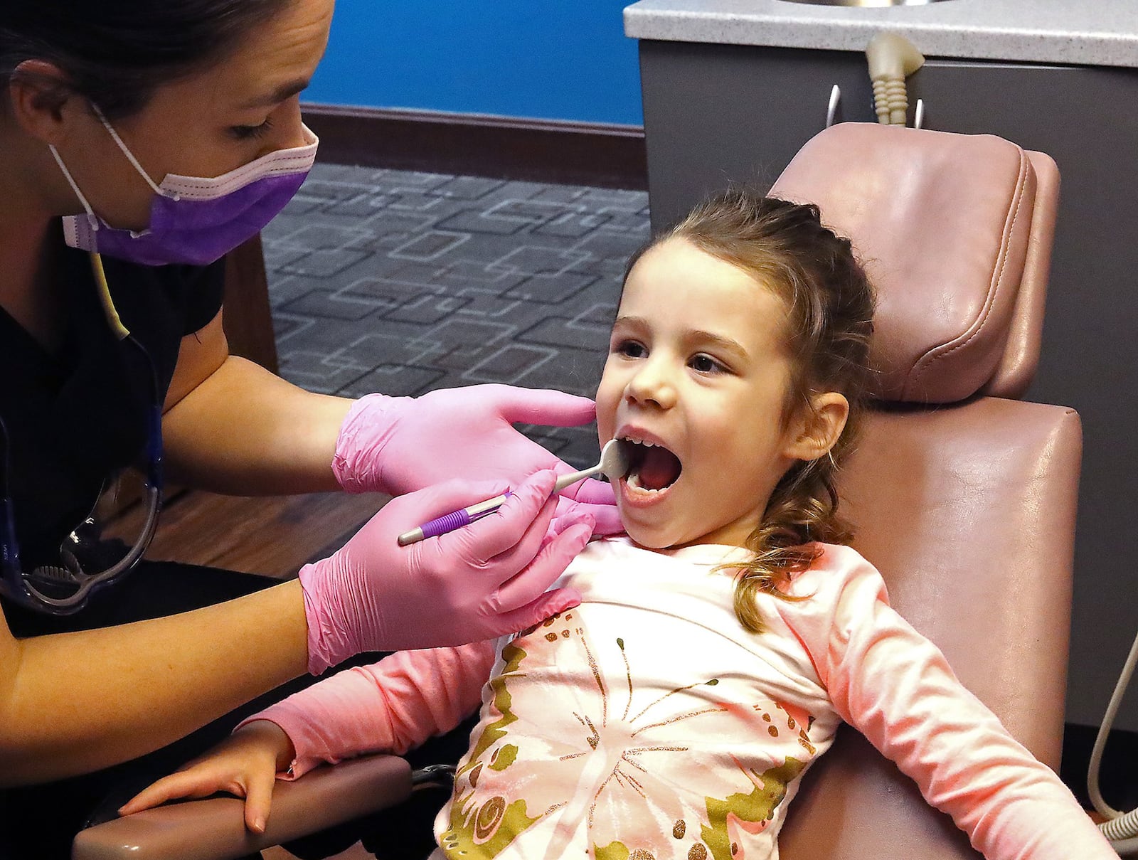 Addie Myers gets her teeth examined by her mother, Dr. Andrea Myers at her pediatric dental office Tuesday. While Clark County ranks among the worst counties in Ohio for children’s dental health, the Springfield community is still divided when it comes to adding fluoride to the public water system. Bill Lackey/Staff