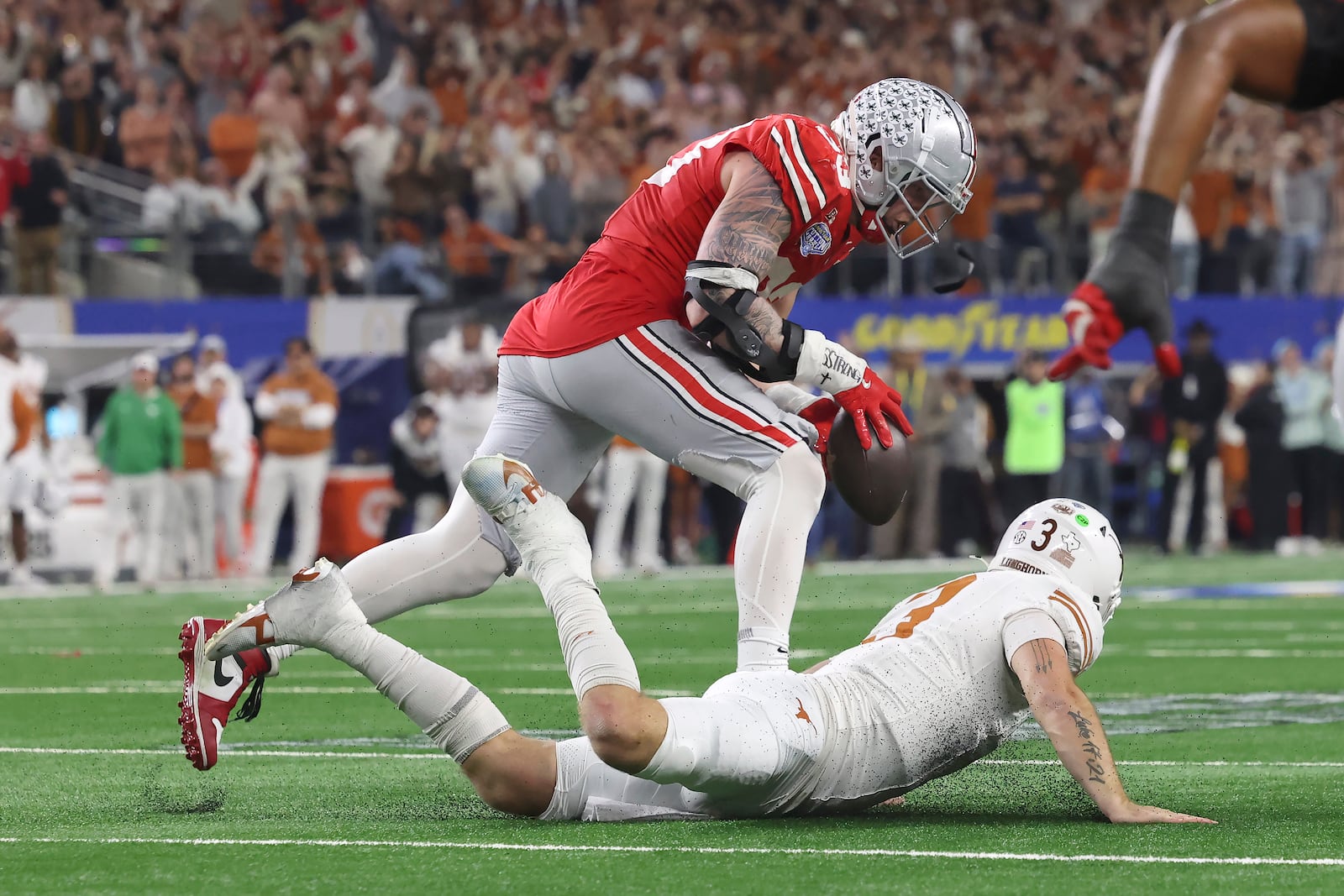 Ohio State defensive end Jack Sawyer, top, runs for a touchdown after recovering a fumble by Texas quarterback Quinn Ewers, bottom, during the second half of the Cotton Bowl College Football Playoff semifinal game, Friday, Jan. 10, 2025, in Arlington, Texas. (AP Photo/Gareth Patterson)