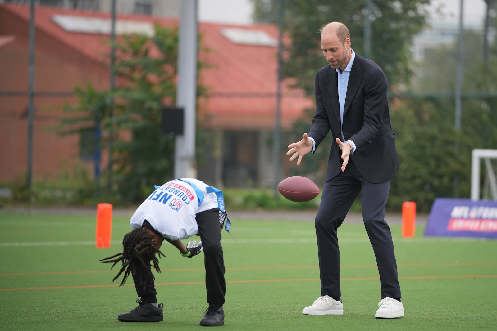 Britain's Prince William catches the football as he attends a NFL Foundation NFL Flag event, an inclusive and fast paced American Football format, in London, Tuesday, Oct. 15, 2024. (AP Photo/Kin Cheung, Pool)