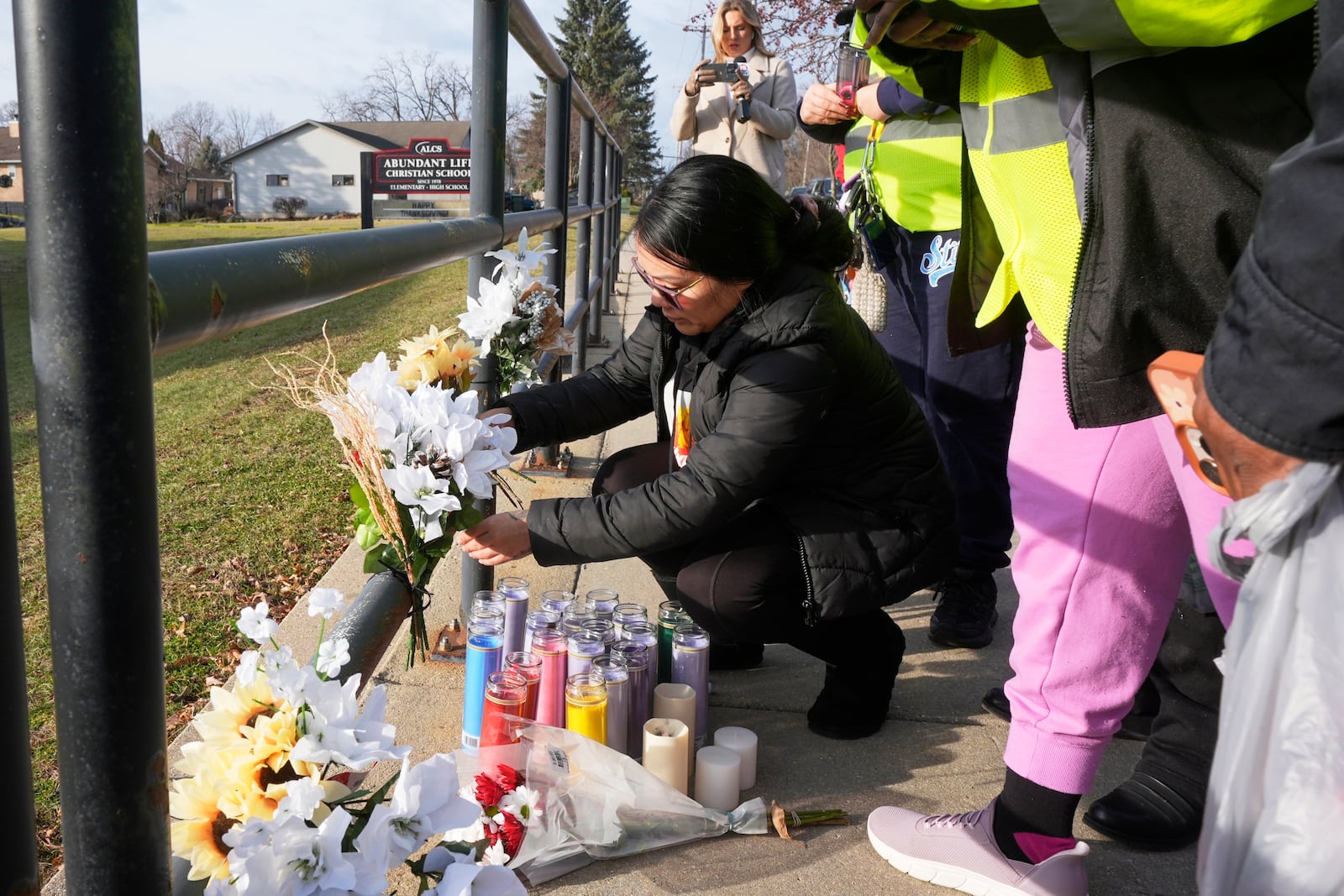 A resident places some flowers outside the Abundant Life Christian School Tuesday, Dec. 17, 2024 in Madison, Wis., following a shooting on Monday. (AP Photo/Morry Gash)