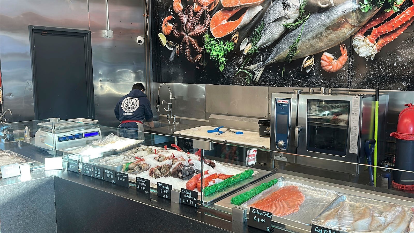 An employee of an Ocean Seafood Depot store works behind the counter, Friday, Jan. 24, 2025, in Newark, N.J. (AP Photo/Ted Shaffrey)