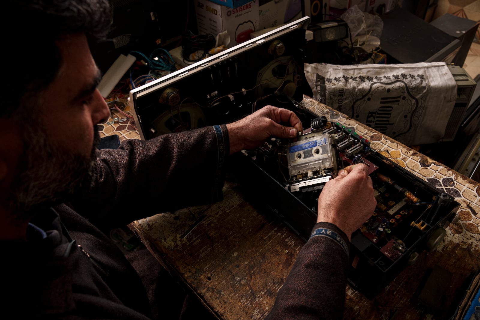 Mohammad Ashraf Matoo repairs a tape recorder inside his shop in Srinagar, Indian controlled Kashmir, Tuesday, Feb. 11, 2025. (AP Photo/Dar Yasin)