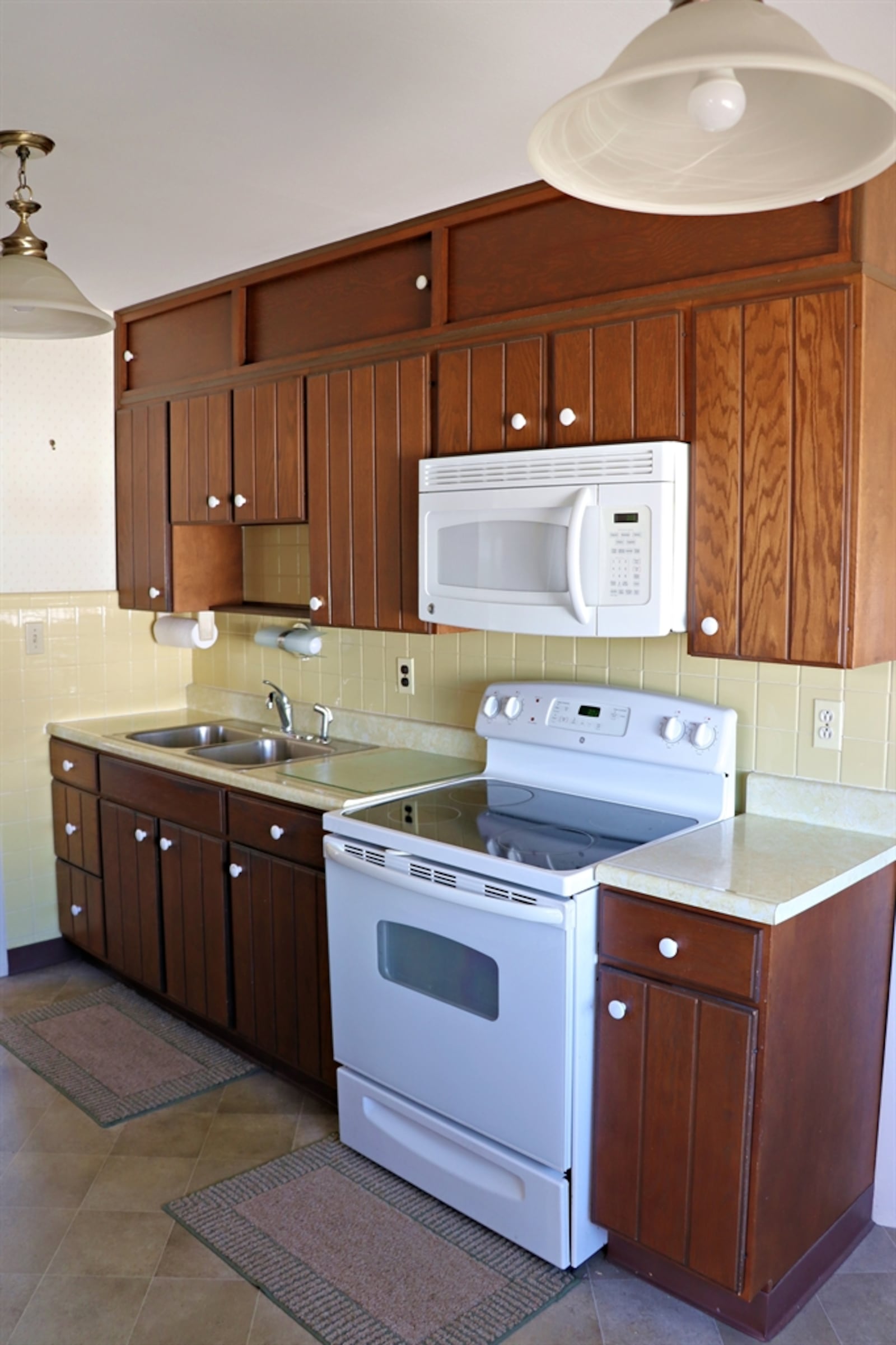 The kitchen is galley style with cabinets and counters along two walls and surrounding the double sink and appliances. 