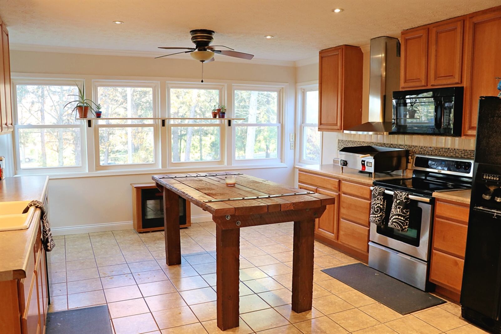 Six windows fill the kitchen with natural light and surround a breakfast room area. Three walls have light maple cabinetry. 