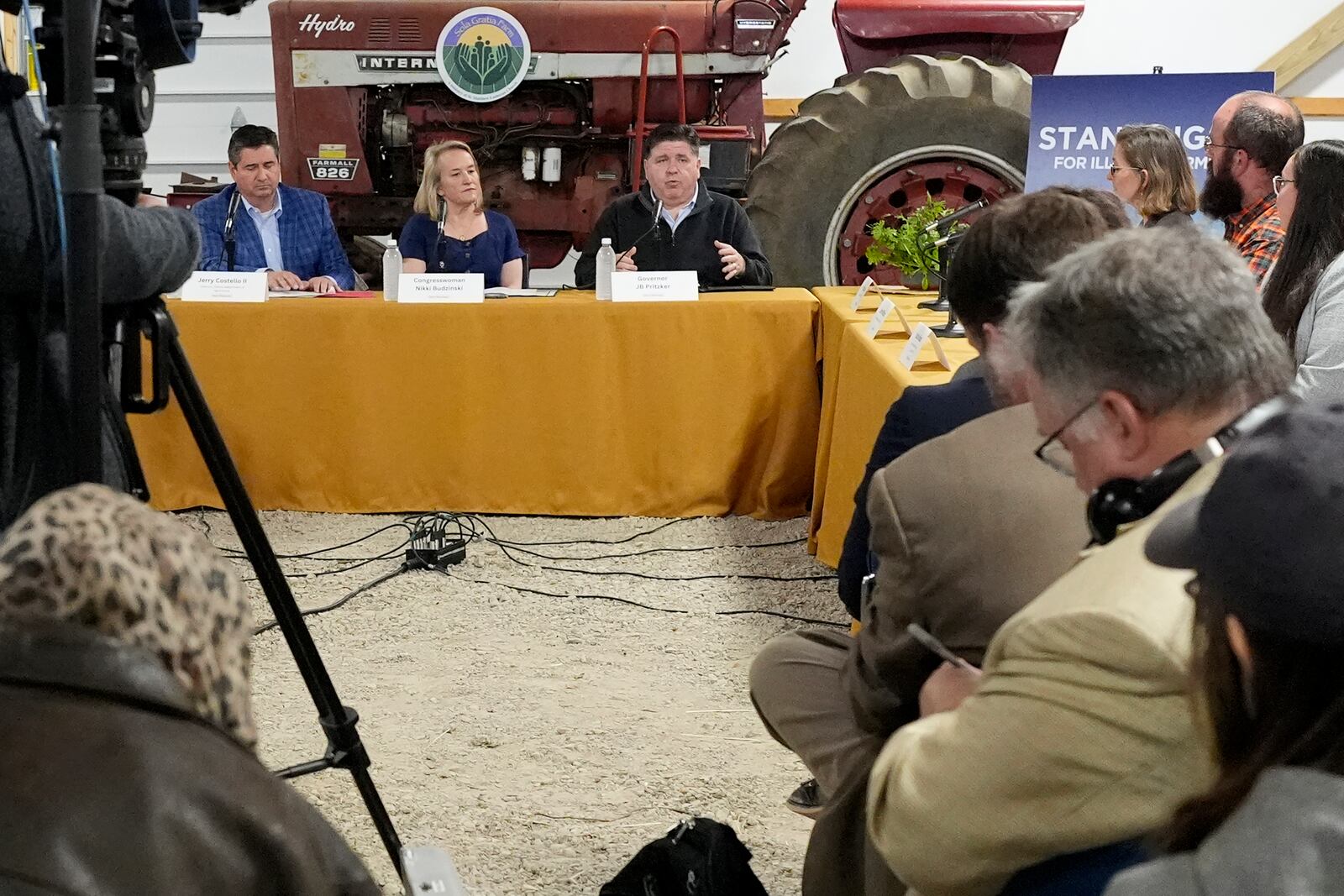 Illinois Gov. JB Pritzker talks as Illinois Department of Agriculture Director Jerry Costello ll, from left, and Rep. Nikki Budzinski, D-Ill., listen during a roundtable discussion on impacts of the Trump Administration's actions on climate-smart agriculture and local farm economy, at Sola Gratia Farm in Urbana, Ill., Wednesday, March 19, 2025. (AP Photo/Nam Y. Huh)